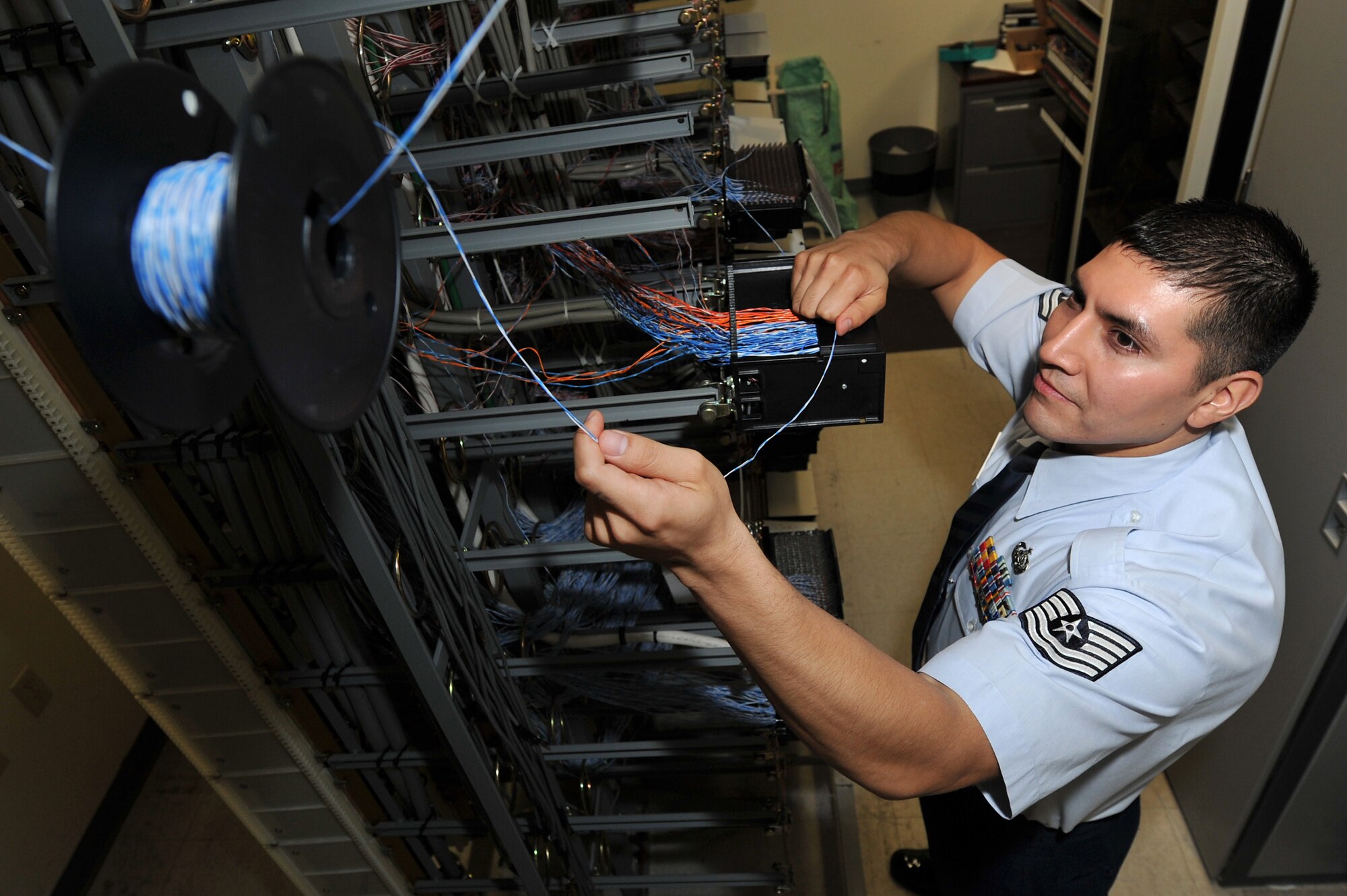 Tech. Sgt. Israel Navarro, a 19th Communication Squadron plans and program manager, pulls jumper wire toward a line equipment number block Nov. 29, 2010, at Little Rock Air Force Base, Ark. Each LEN block consolidates the phone lines and then distributes them out to buildings across the base. (U.S. Air Force photo by Staff Sgt. Chris Willis)