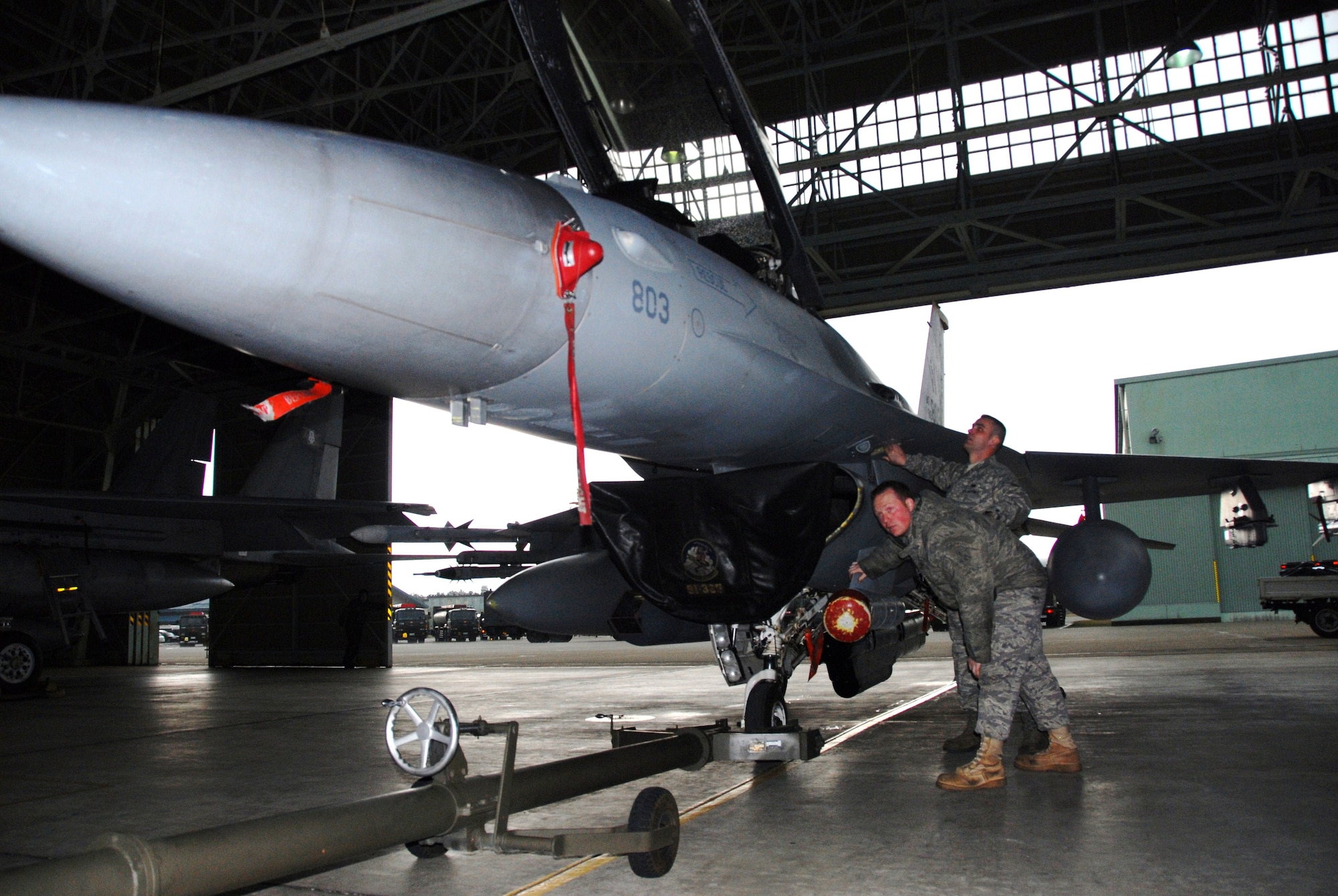 U.S. Air Force Staff Sgts. Robert Ensley, front, and Robert White, 35th Aircraft Maintenance Squadron, prepare an F-16 Fighting Falcon for storage inside a Komatsu Air Self-Defense Force Base hangar, during a Keen Sword exercise mission Dec. 3, 2010. A large and complex exercise, Keen Sword 2011 involves joint U.S. forces and Japanese Self-Defense Forces from all components of both militaries training to conduct bilateral operations in support of the defense of Japan. (U.S. Air Force photo by 1st Lt. Cammie Quinn/ Released)