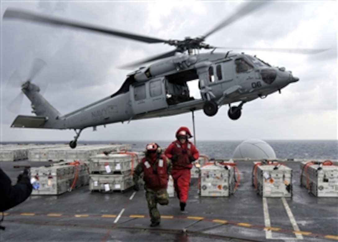 U.S. Navy Airman Erik Fischer and Petty Officer 3rd Class Ryan Caballero leave a staging area as an MH-60S Sea Hawk helicopter assigned to Helicopter Combat Support Squadron 25 lifts ordnance from the flight deck of the aircraft carrier USS George Washington (CVN 73) underway off the coast of the Korean peninsula on Dec. 2, 2010.  The George Washington recently completed a training exercise with the South Korean navy.  