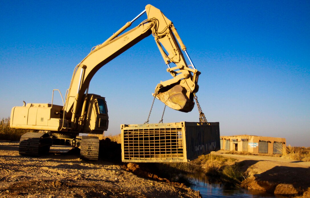 A heavy equipment vehicle belonging to Marines with Engineer Company, Combat Logistics Battalion 3, 1st Marine Logistics Group (Forward) prepares to emplace a metal storage container to be used as a bridge in Marjah, Afghanistan, Dec. 3. Combat engineers with CLB-3 constructed a bridge and guard post in support of Marine units operating in the area.