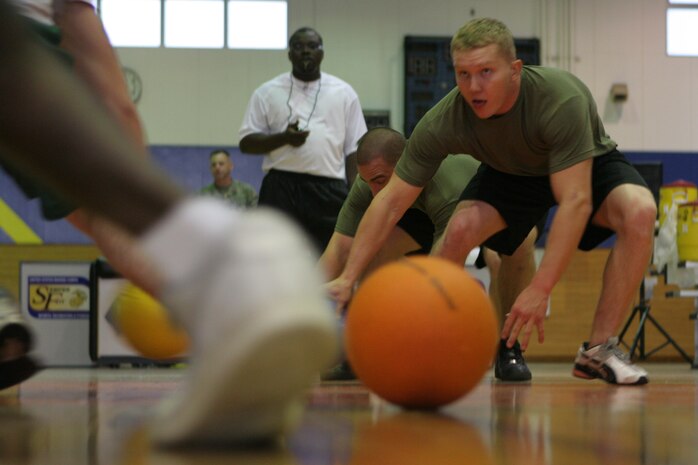 In an attempt to snag one of the six balls Robert Griffin, Munis team member, races to the half court line during the intramural dodgeball tournament at the IronWorks Gym sports court here Saturday. Munis won second place to the Rack Inspectors in the tournament. Jason D. Hulette, Munis team member, brought out his immediate work center because he wanted to help get the Marines in his section to be more active.