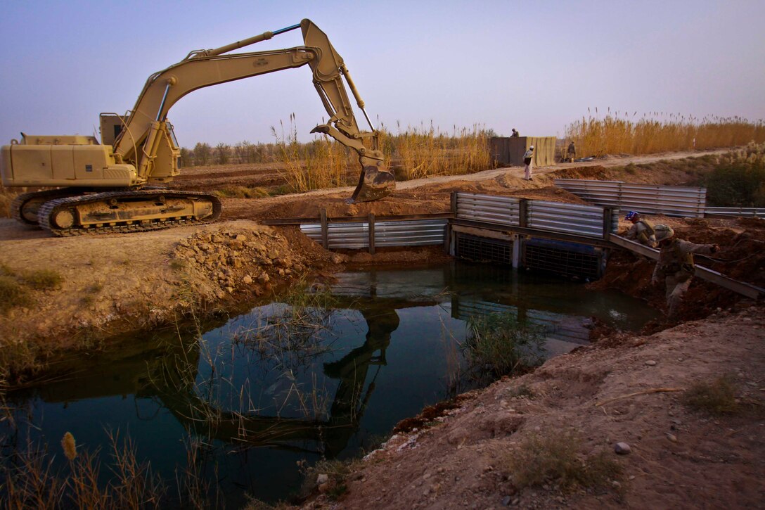 A heavy equipment vehicle operated by Marines with Engineer Company, Combat Logistics Battalion 3, 1st Marine Logistics Group (Forward) finalizes construction on a beidge in Marjah, Afghanistan, Dec. 4. Combat engineers with CLB-3 constructed a bridge and guard post in support of Marine units operating in the area.