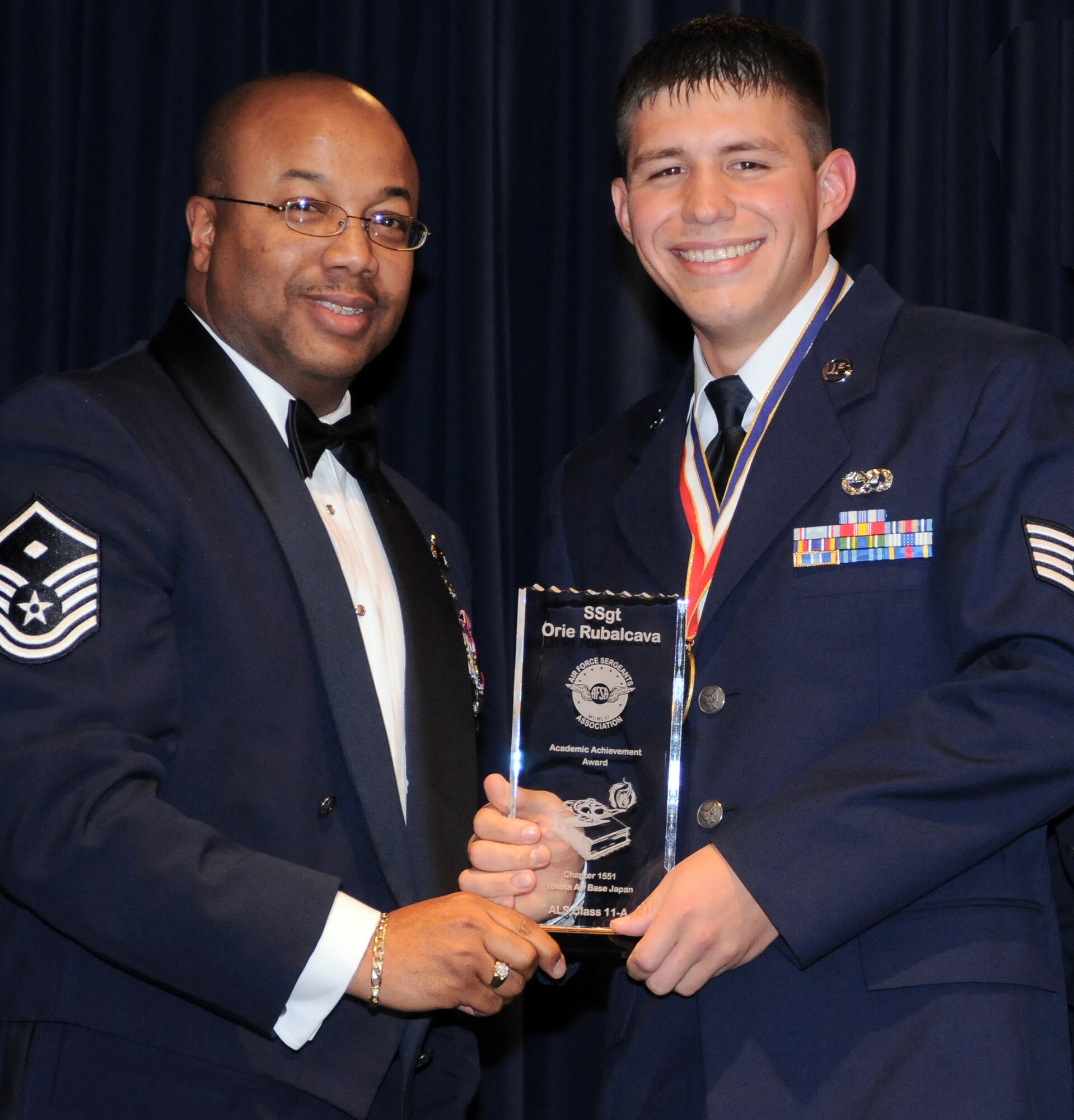YOKOTA AIR BASE, Japan -- Staff Sgt. Orie Rubalcava, 374th Maintenance Squadron, receives the Academic Achievement Award, from presenter Master Sgt. Derrick Harper, 374th Force Support Squadron first sergeant, during the Airman Leadership School graduation ceremony held at the Yokota Enlisted Club here Dec. 2.  Rubalcava also received the Distinguished Graduate Award. (U.S. Air Force photo/ Airman 1st Class Katrina R. Menchaca)