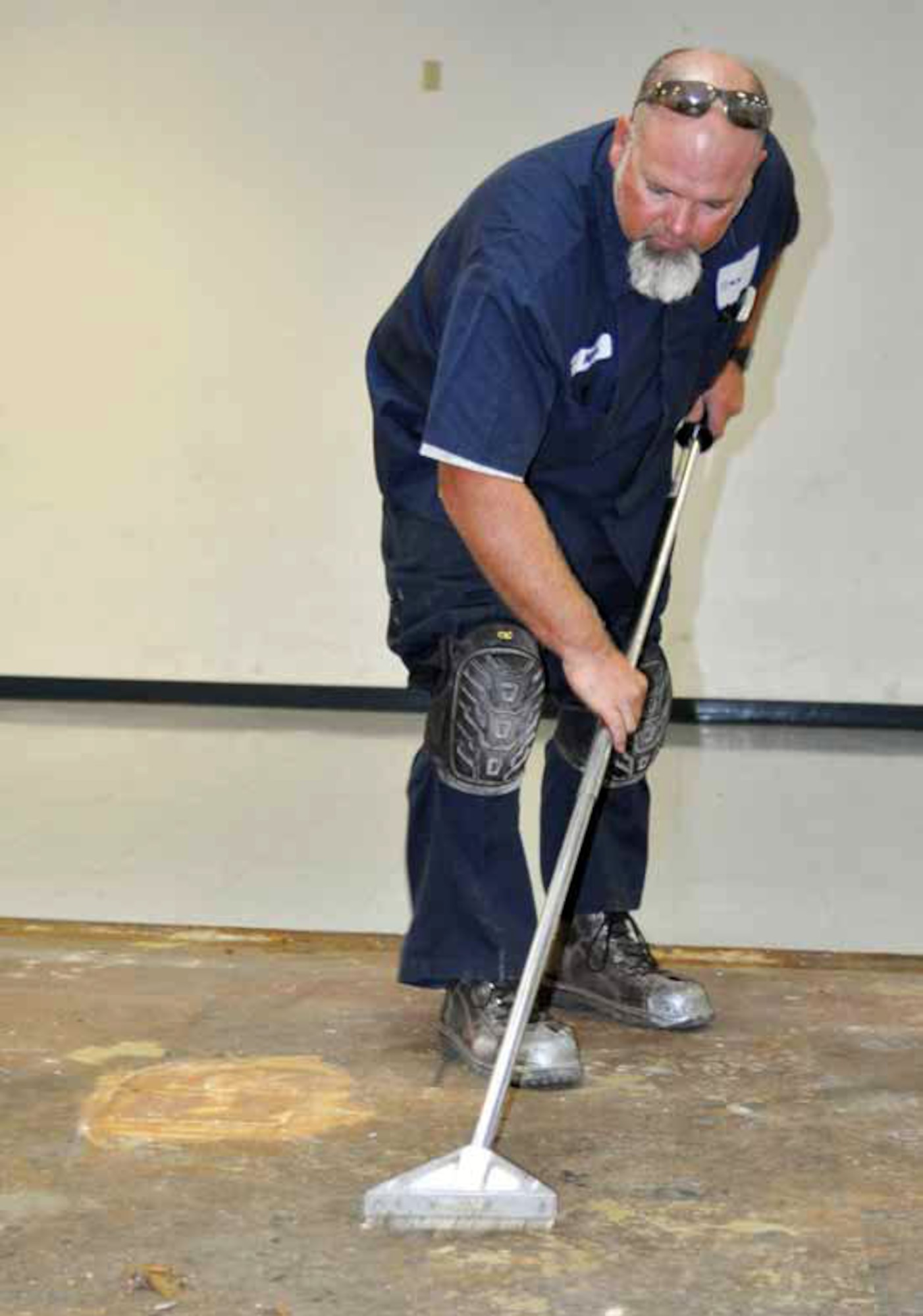 Mike Hudson, a Satellite Services, Inc. employee, prepares a floor for tiling at the 452nd Security Forces Squadron building, Nov. 16. The squadron replaced the raised floor with tile so they could conduct ground combat training.  (U.S. Air Force photo by Linda Welz)
