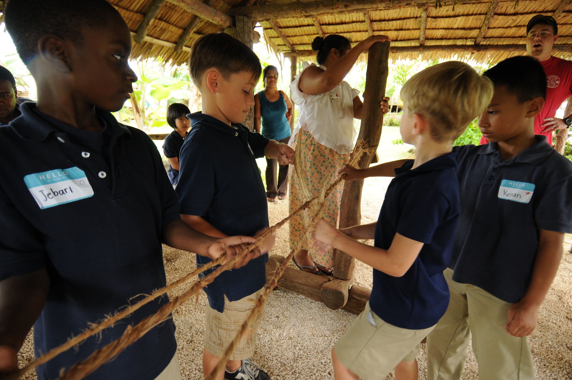 Students from Andersen Elementary School assist a tour guide at Gef Pa’go Chamorro Cultural Village in making rope during a recent field trip to the village.  The rope, which is made out of dried out wild hibiscus fibers, are twisted individually into three strands then twisted together to form the rope. (U.S. Air Force photo by Master Sgt. Carrie Hinson/Released)