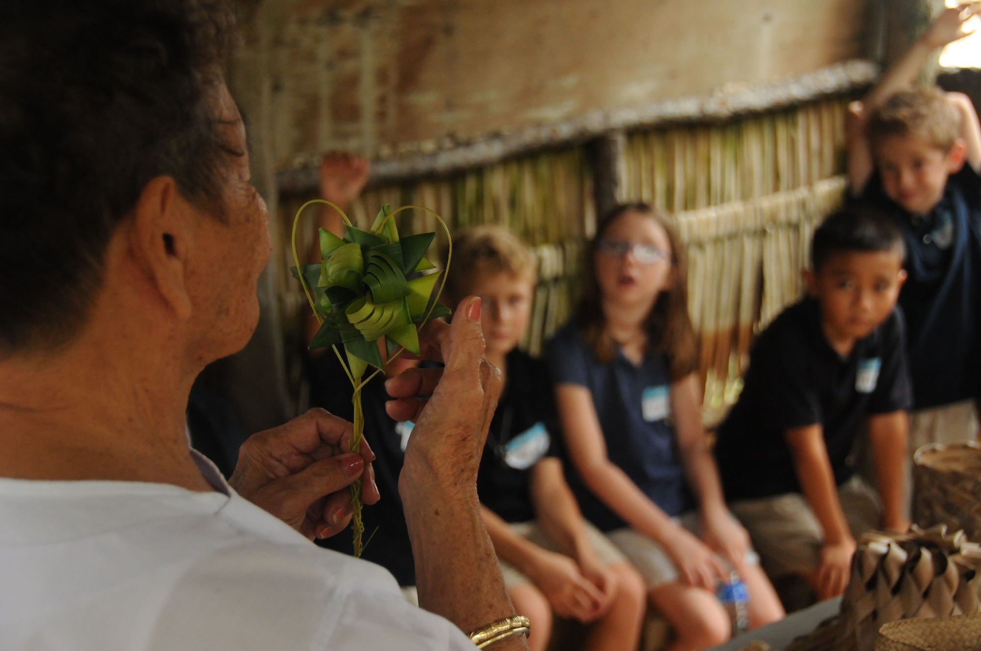 Tan Floren displays a decoration she made out of coconut leaves to Andersen Elementary 2nd graders during a recent field trip to Gef Pa’go Chamorro Cultural Village in Inarajan Bay.  Floren, a master weaver, has been weaving since she was a young girl and now shares her craft with others. (U.S. Air Force photo/Master Sgt. Carrie Hinson)