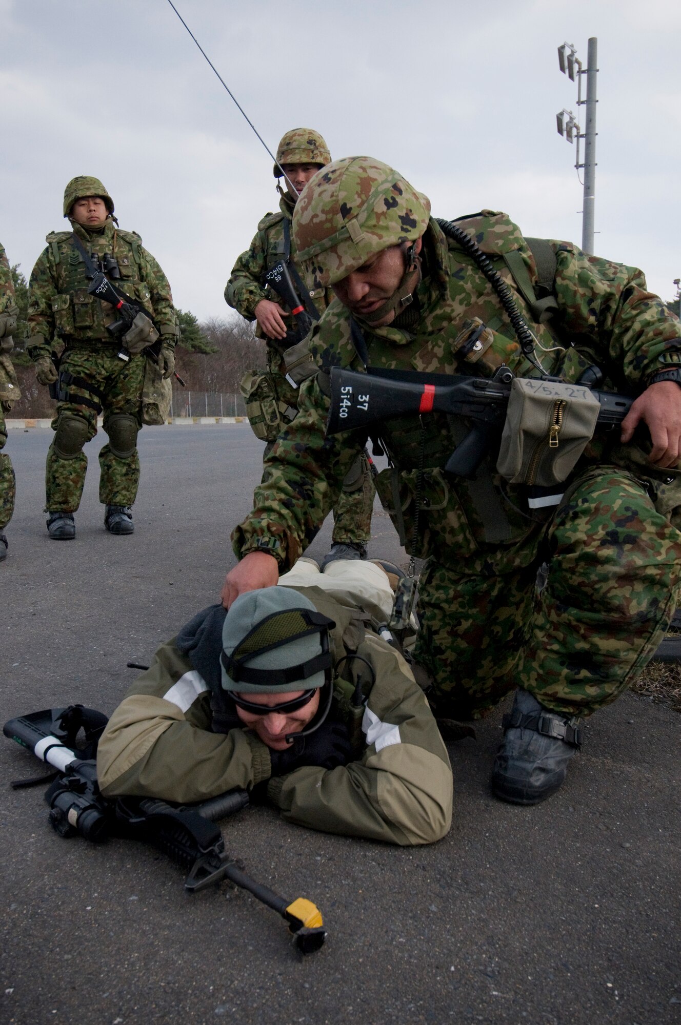 A Soldier from Japan Ground Self Defense Force, 9th Division, 5th Infantry Regiment, Aomori, verifies a simulated kill on Tech. Sgt. Paul Barentine, 35th Security Forces Squadron and opposing forces members, Dec. 5, 2010, during a bilateral exercise at Misawa Air Base, Japan. The JGSDF troops were part of a two-day Guard and Protect Exercise that partnered them with the Japan Air Self-Defense Force 3rd Air Wing and the 35th Security Forces Squadron. (U.S. Air Force photo by Senior Airman Jessica Lockoski/Released)