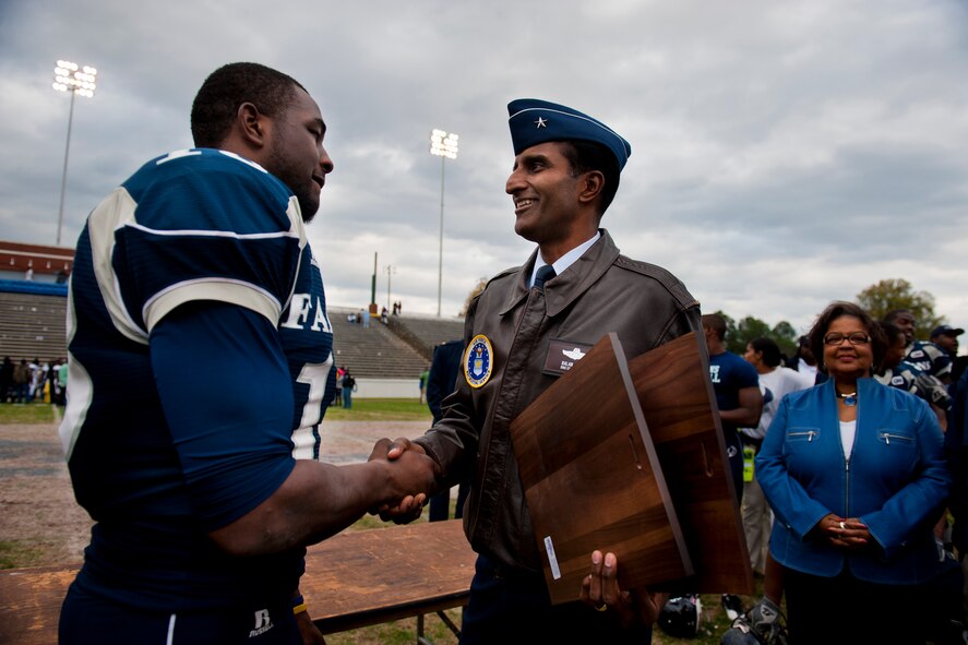 COLUMBUS, Ga. -- Brig. Gen. Balan Ayyar, Air Force Recruiting Service commander, congratulates Jone' Harris, St. Augustine's College Falcons tight end, for earning the 2010 Pioneer Bowl Most Valuable Player and Offensive MVP awards during his team's 20-9 victory over the Fort Valley State University Wildcats Dec. 4 at the A.J. McClung Memorial Stadium. Mr. Harris caught three passes for 54 yards and scored two touchdowns. He is a senior majoring in mathematics. In the background, Dr. Dianne Boardley Suber, St. Augustine's College president, awaits her star athlete. (U.S. Air Force photo/Senior Airman Jamal D. Sutter)(RELEASED)