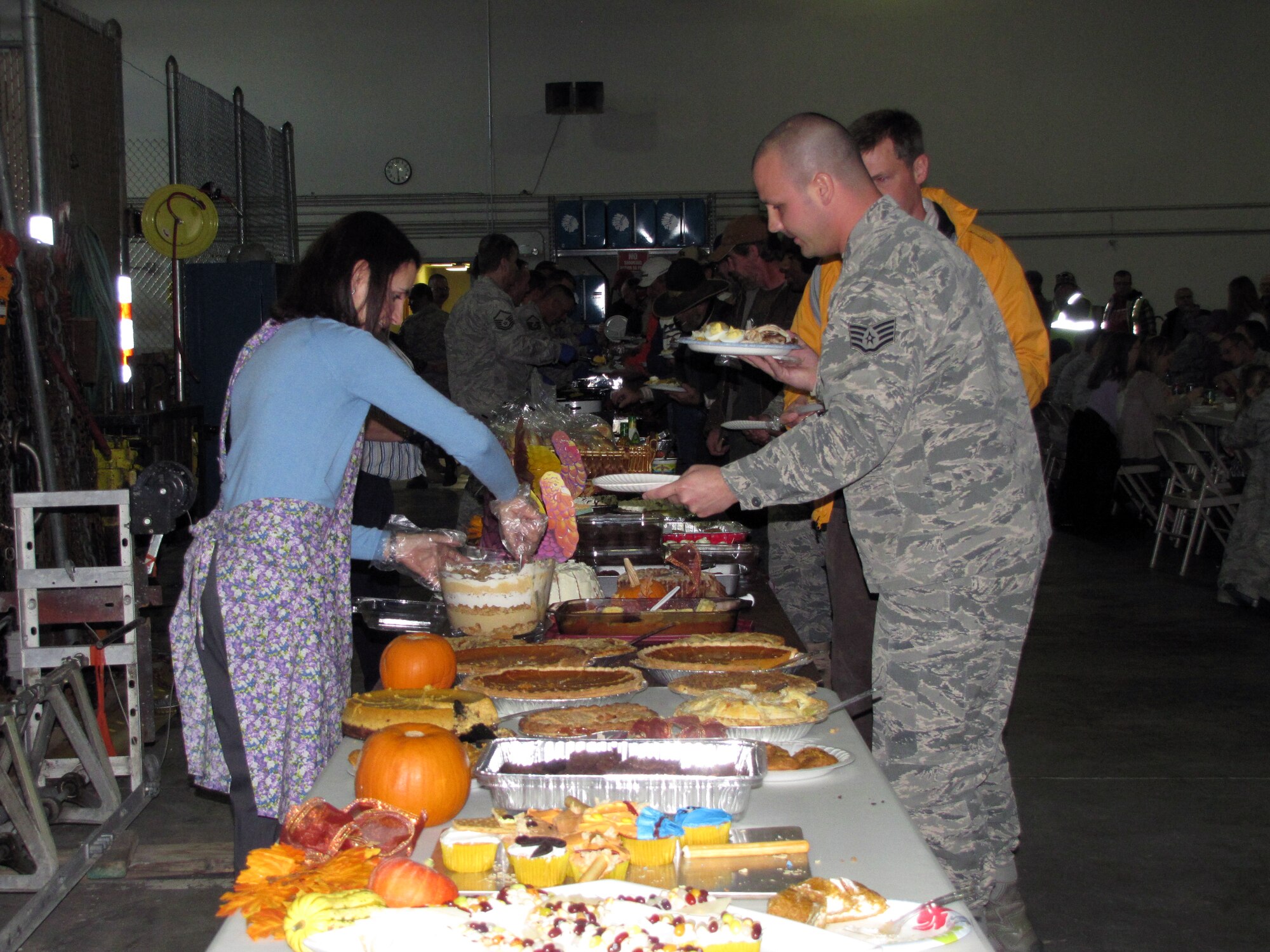 Jenni Roberts, wife of Lt. Col. Charles Roberts, 90th Civil Engineer Squadron commander, serves members of the 90th CES desserts during the 90th CES annual turkey feed held at Building 930, 90th CES pavement and equipment shop on Nov. 16 date. There were 23 fried and baked turkeys, nine hams and more than 44 desserts available for people to eat. The annual turkey feed started back in 1975, and continues on today. (Courtesy photo)