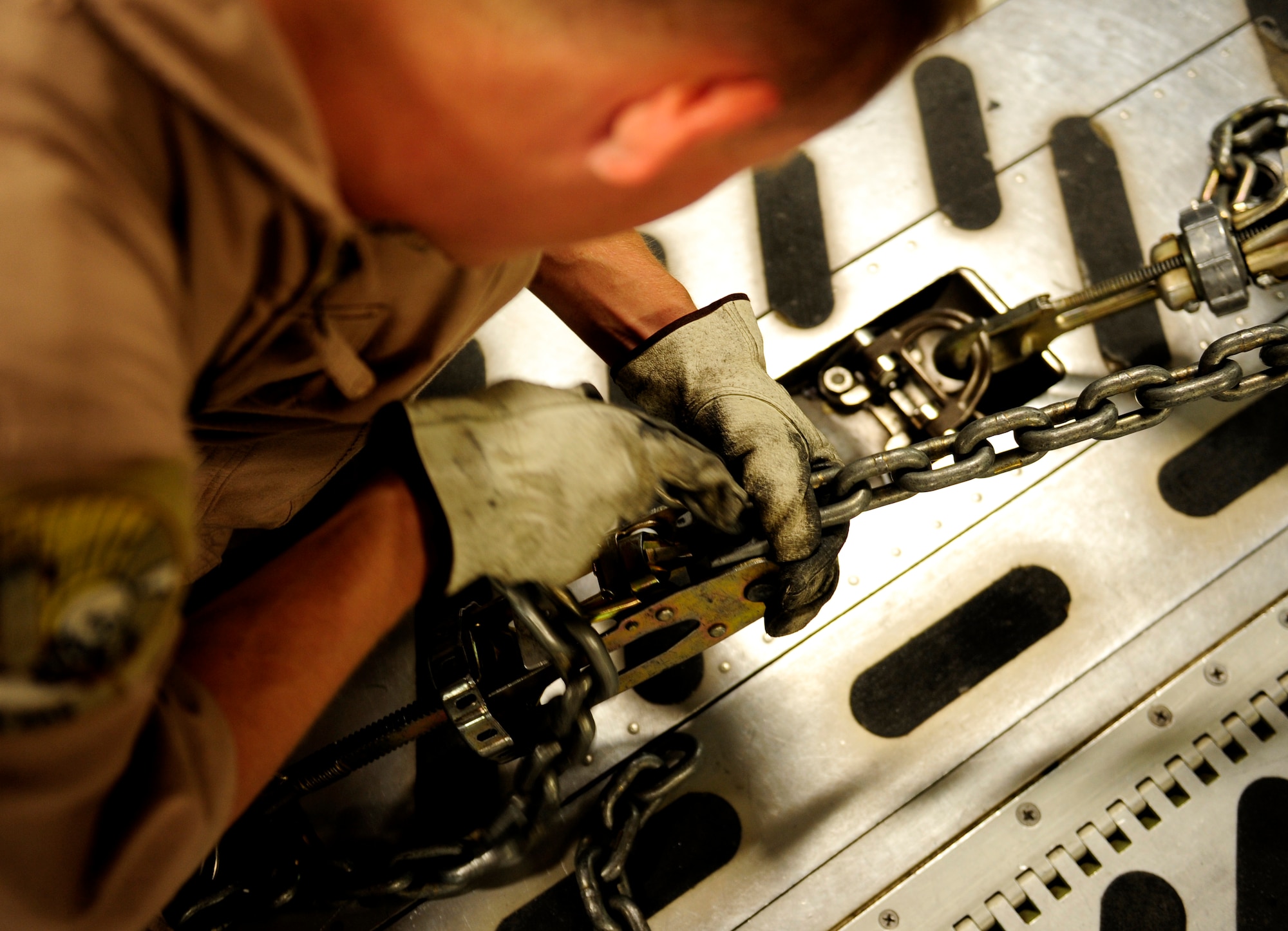 Senior Airman Timothy Glover, a C-17 Globemaster III aircraft loadmaster assigned to the 816th Expeditionary Airlift Squadron at a non-disclosed base in Southwest Asia, locks chains in place to secure a Marine Corps M1A1 Abrams tank to the floor of the aircraft en route to Afghanistan in support of Operation Enduring Freedom on Nov. 28, 2010. (U.S. Air Force Photo/Staff Sgt. Andy M. Kin)