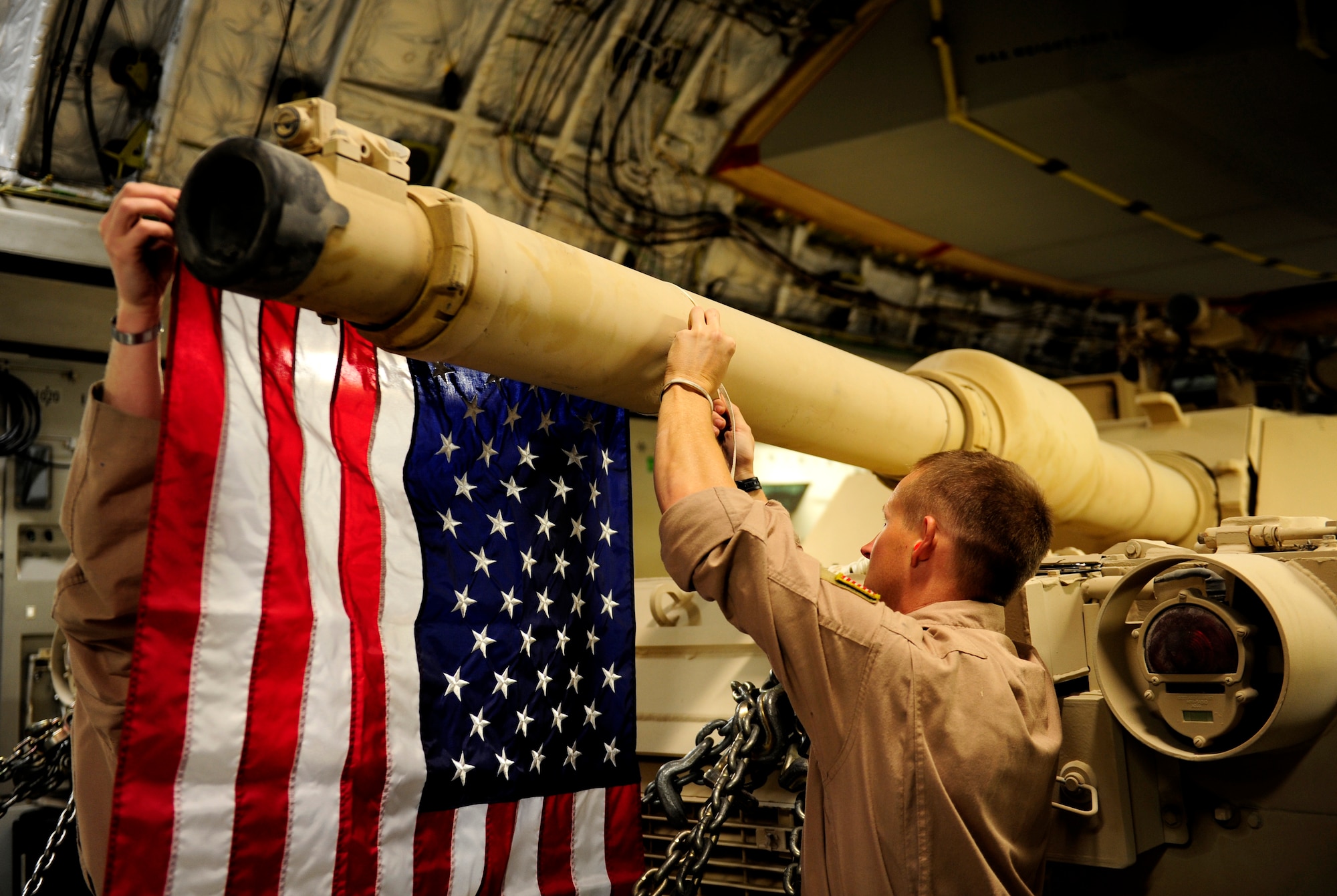 U.S. Air Force C-17 Globemaster III aircraft crew members assigned to the 816th Expeditionary Airlift Squadron at a non-disclosed base in Southwest Asia, tie an American flag onto a Marine Corps M1A1 Abrams tank during an air transport to Afghanistan in support of Operation Enduring Freedom on Nov. 28, 2010. (U.S. Air Force Photo/Staff Sgt. Andy M. Kin)