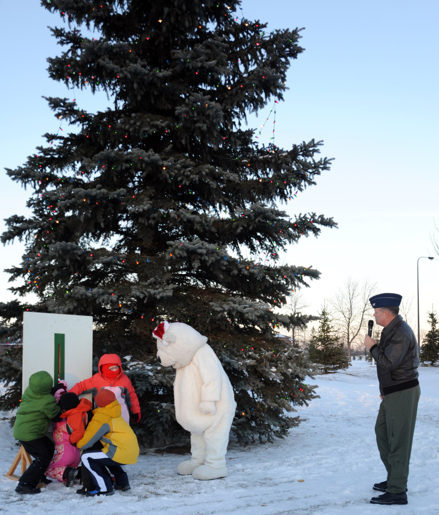 Col. Don Shaffer, 319th Air Refueling Wing commander, watches as children of the Warriors of the North and Dakota the bear, pull the light switch down to officially light the holiday tree during the annual holiday tree lighting ceremony Dec. 1 outside of the base fitness center. (U.S. Air Force photo by Staff Sgt. Suellyn Nuckolls)