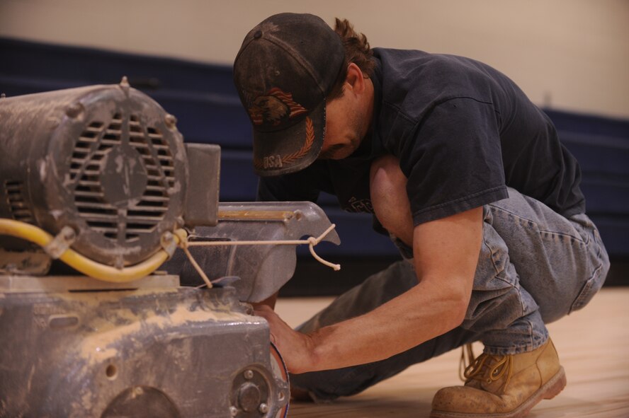 MOODY AIR FORCE BASE, Ga. -- Mike Webb, contracted worker, installs a new strip of sandpaper on a riding sander at the basketball court in the Freedom I Fitness Center Dec. 1. The riding sander spins the sandpaper at 600 rpm to level floors and remove the wax. (U.S. Air Force Photo/Airman 1st Class Douglas Ellis)(RELEASED)