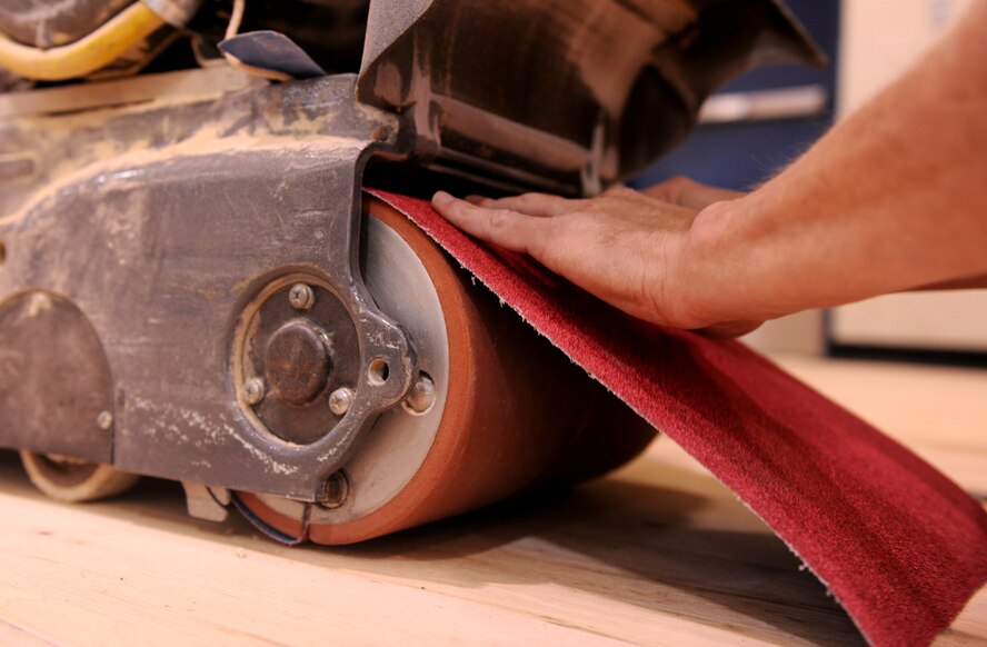 MOODY AIR FORCE BASE, Ga.-- Sandpaper is placed into the riding sander as contract workers refinish the Freedom I Fitness Center’s gym floor Dec. 1. The riding sander removes the top layer of the floor by rotating sandpaper on a spool at nearly 600 rpm.  (U.S. Air Force photo/Airman 1st Class Benjamin Wiseman)(RELEASED)