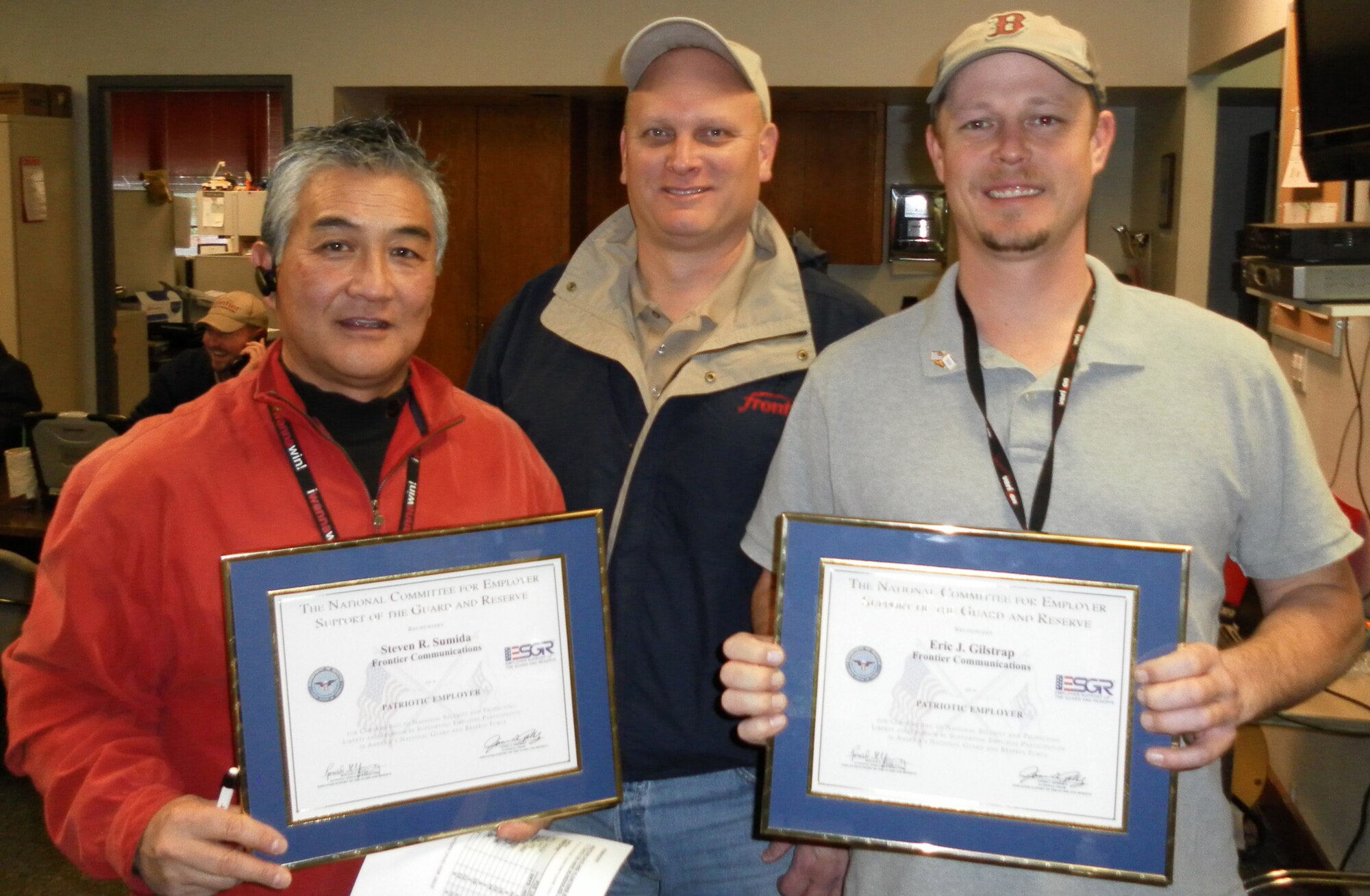 Steven Sumida, left, and Eric Gilstrap, right, Frontier Communications managers in Beaverton, Ore., receive the Patriot Award from the Employer Support of the Guard and Reserve on Nov. 10.  Staff Sgt. Michael Pritchett, center, 36th Aerial Port Squadron ramp specialist here, nominated Frontier Communications for the award.  Sergeant Pritchett is also a technician for Frontier Communications in his civilian job.