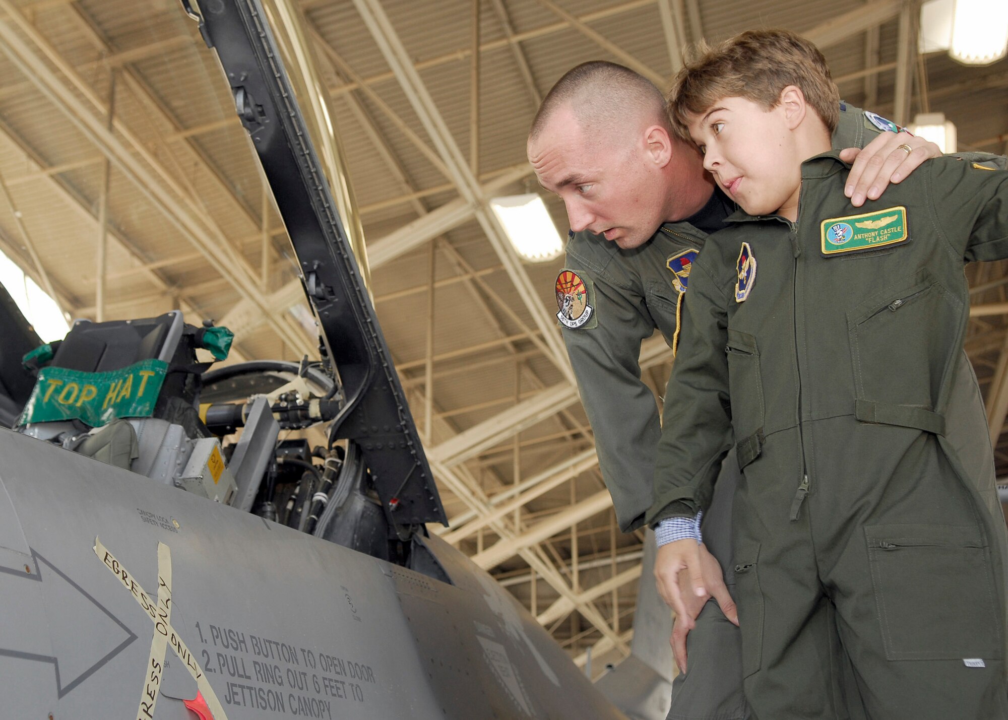 Capt. Christopher Jones, 310th Fighter Squadron pilot, and Anthony "Flash" Castle, 11, look inside the cockpit as Anthony prepares to enter the F-16 Fighting Falcon on November 19th during pilot-for-a-day.  (U.S. Air Force photo/Staff Sgt. Louis Vega Jr.)