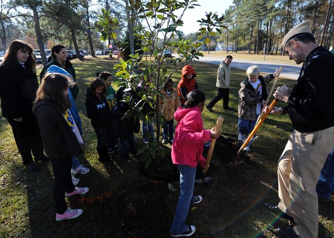 Students from Marrington Elementary School cover tree roots with Navy Capt. Ralph Ward during an Arbor Day event at their school Dec. 3, 2010, on Joint Base Charleston-Weapons Station, S.C. The base officially became a member of the Tree City USA foundation after fulfilling the last of many requirements, earning them the membership in Tree City USA. In previous years, Charleston Air Force Base and Naval Weapon Station Charleston had been members of Tree City USA, but are now officially members as a joint base. Captain Ward is the JB CHS deputy commander. (U.S. Air Force photo/Senior Airman Timothy Taylor)