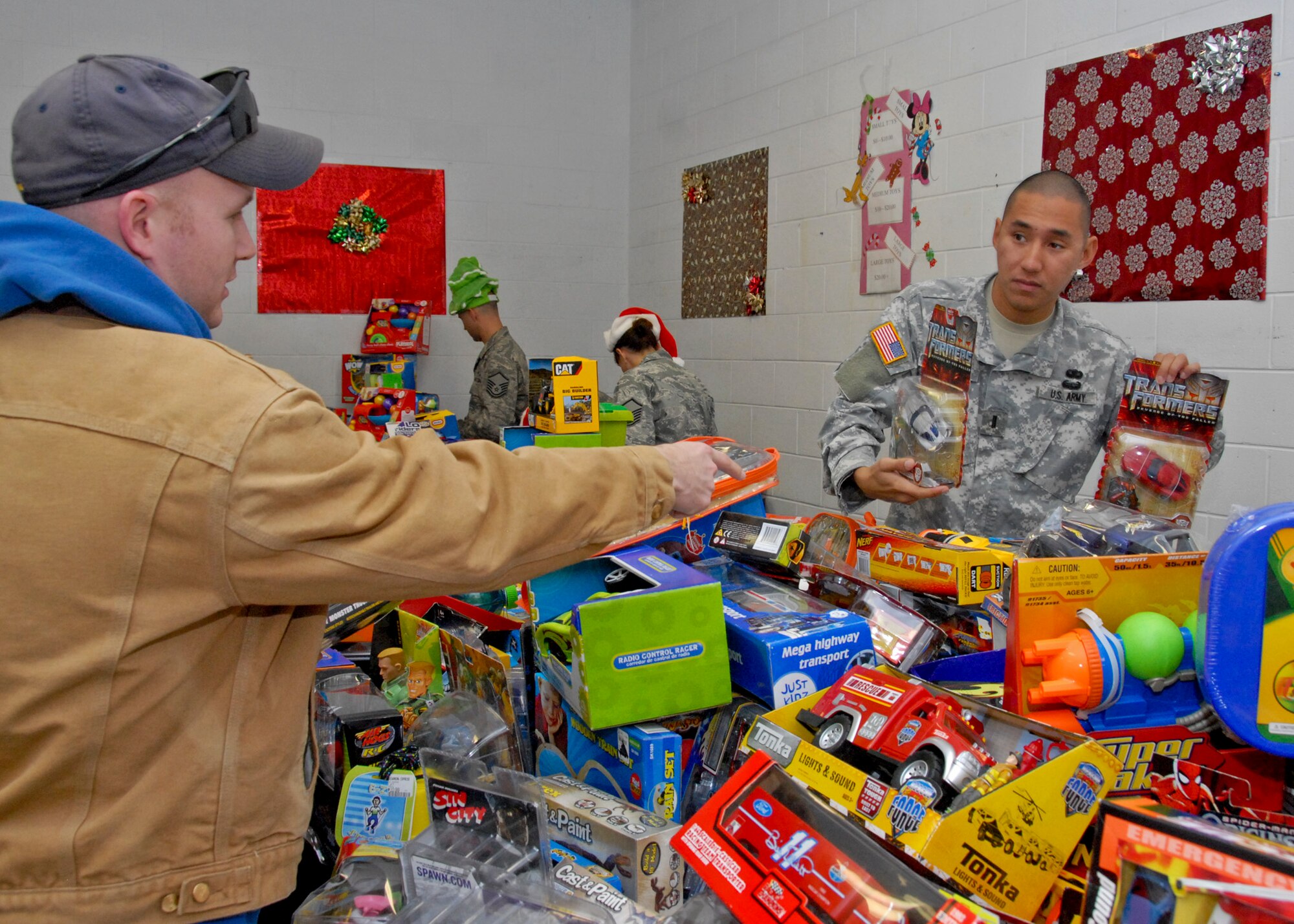 With the help of a volunteering service member, Billy Byrd picked out the perfect gift for his child at the toy distribution at the Airman's Attic Dec. 2. Over 2,400 toys were given out to 502 children. (U.S. Air Force photo/Sachel Seabrook)

