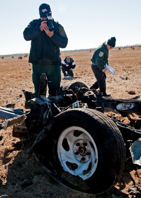 Detective William Punausuia, Leon County Sheriff's Department, photographs the wreckage of a pickup truck, while team leader, Sgt. John Corley, Bay County Sheriff's Department, takes notes during the investigation of a created crime scene Dec. 1 at  Eglin Air Force Base, Fla.  The investigations were part of the FBI's large vehicle post blast school attended by state and local law enforcement agencies as well as Marine and Air Force explosive ordnance disposal technicians. Three vehicles were blown up to create the crime scenes that students would investigate.  This was the largest class held in the U.S. and the first ever here.(US Air Force photo/ Samuel King) 