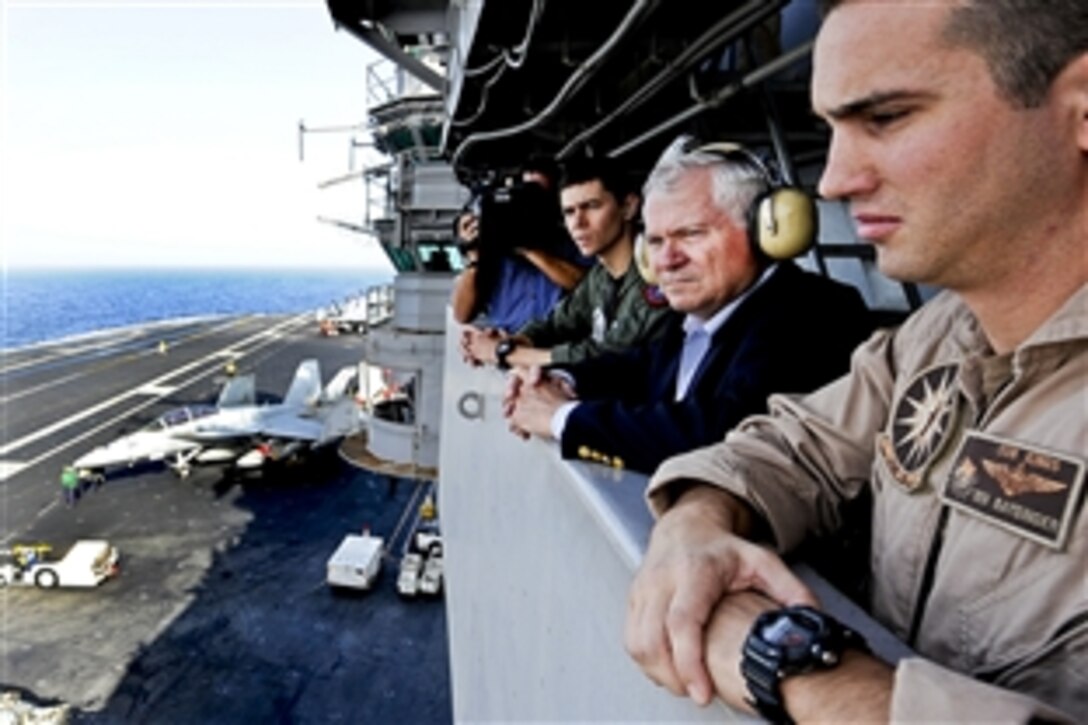 U.S. Defense Secretary Robert M. Gates visits "Vulture's Row" and observes launches and recoveries while aboard the USS Abraham Lincoln in the Arabian Sea, Dec. 6, 2010.