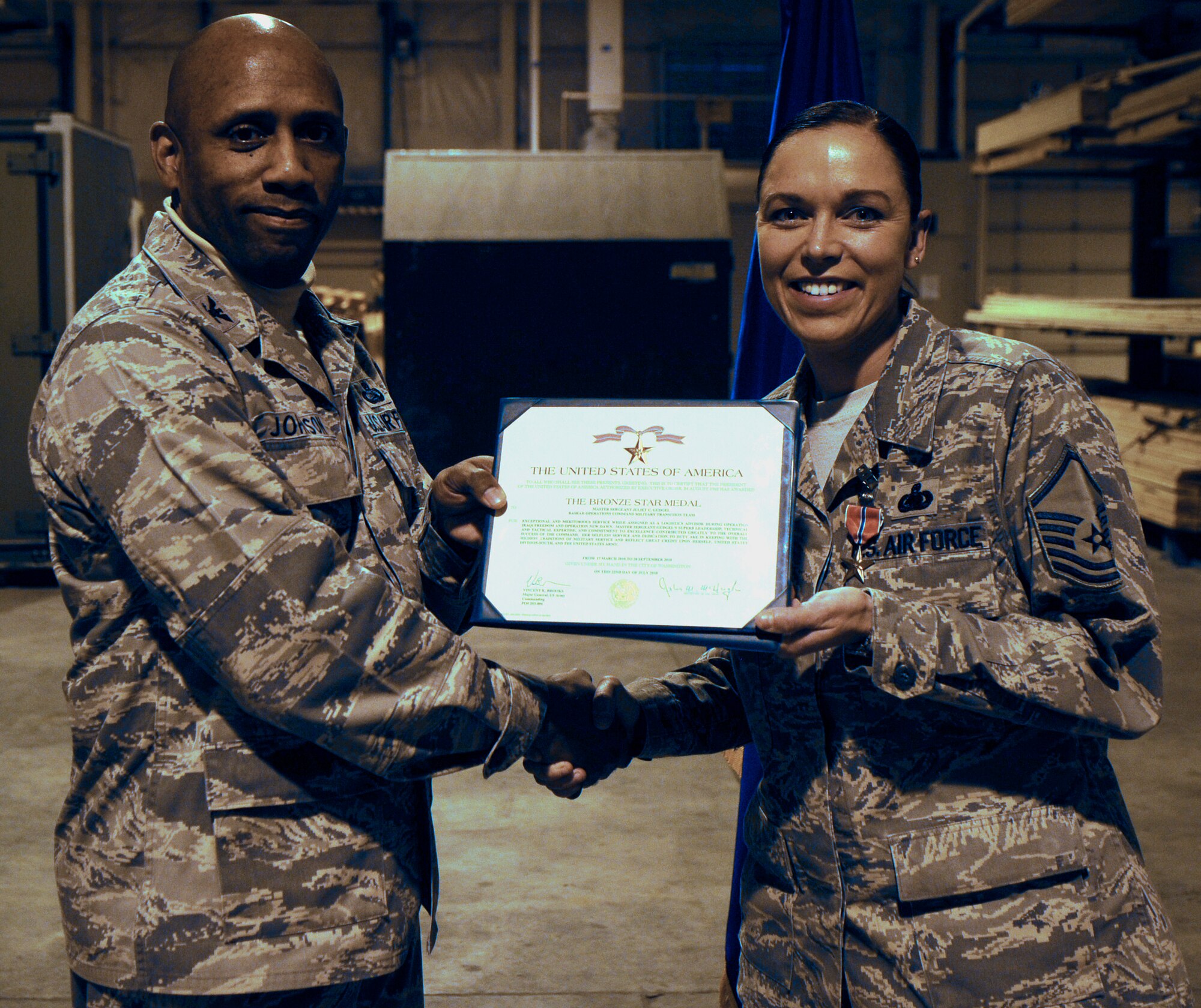 Master Sgt. Juliet Gudgel shakes hands with Col. Karlton Johnson while receiving Bronze Star medal Nov. 30, 2010, Eielson Air Force Base, Alaska.  Sergeant Gudgel distinguished herself by exceptionally meritorious service to the U.S. during Operation Iraqi Freedom and Operation New Dawn.  She is assigned to the 354th Logistics Readiness Squadron as the quality assurance superintendent.  (U.S. Air Force photo/Airman 1st Class Yash Rojas)