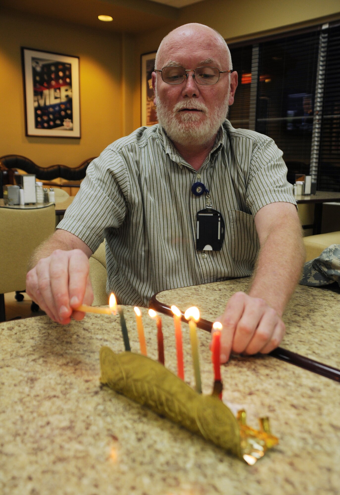 SOTO CANO AIR BASE, Honduras --  Mr. Bruce Drube, who works with the Army Support Activity here, lights the sixth candle of the Menorah with the shamash during the sixth night of Chanukah hosted by the Chapel here Dec. 6. Chanukah is an eight-day Jewish holiday commemorating the rededication of the Holy Temple in Jerusalem. (U.S. Air Force photo/Tech. Sgt. Benjamin Rojek)