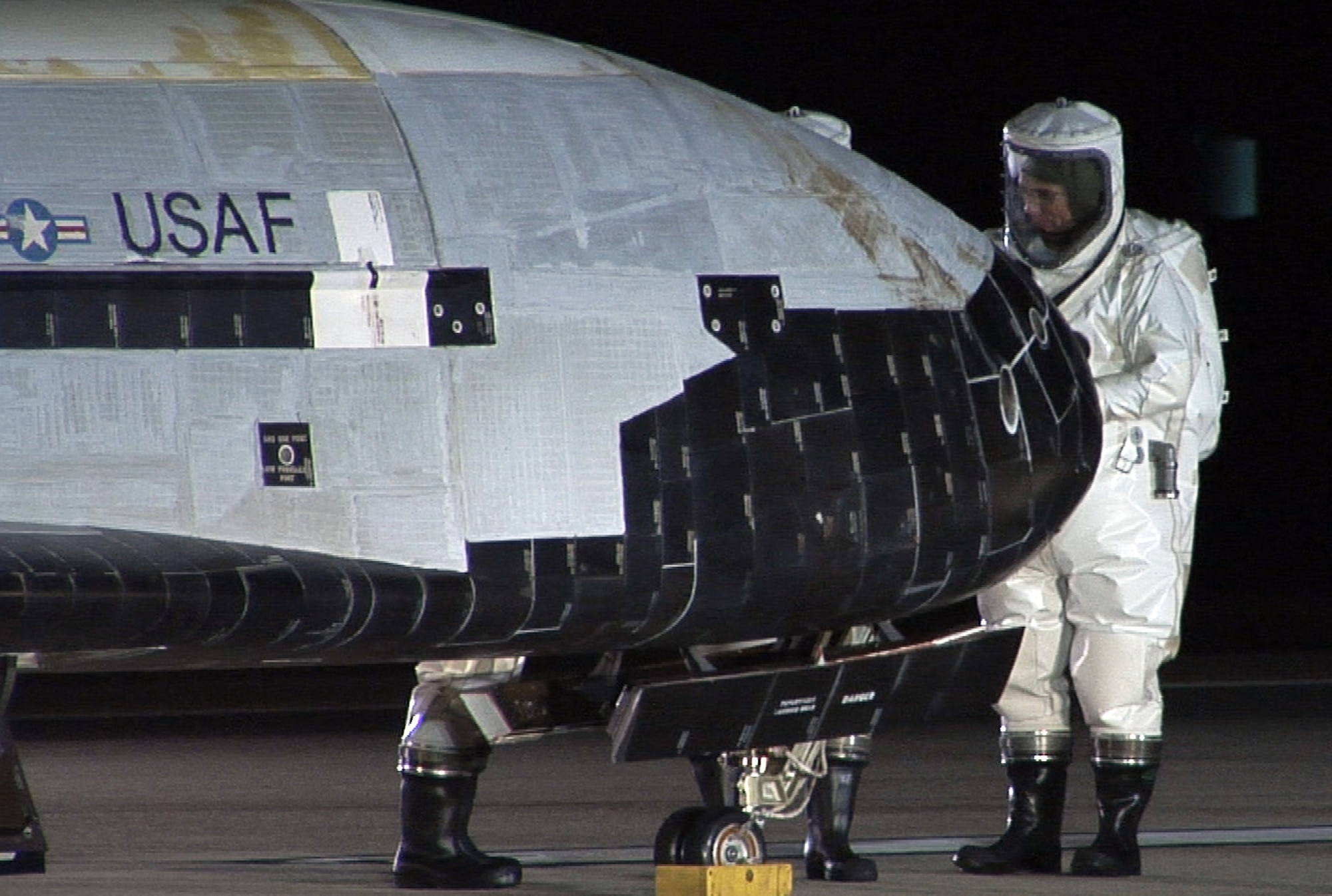 The X-37B Orbital Test Vehicle sits on the runway at Vandenberg Air Force Base, Calif., Dec. 3, 2010, during post-landing operations. Personnel in self-contained atmospheric protective ensemble suits are conducting initial checks on the vehicle and ensuring the area is safe. The X-37B launched April 22 from Cape Canaveral, Fla., allowing teams to conduct on-orbit experiments for more than 220 days during this first mission. (U.S. Air Force photo/Michael Stonecypher)
