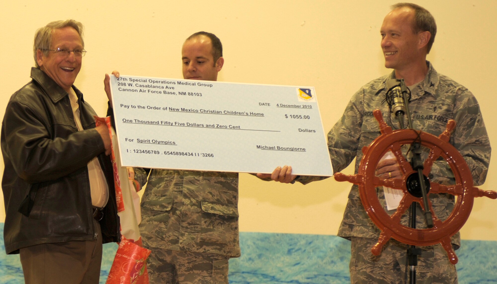 Col. Scott Corcoran, commander of the 27th Special Operation Medical Group, presents a check for $1,055 to Charles Henderson, the executive director of the Christian Children's Home in Portales, N.M., Dec. 5th. The 27th SOMDG raised the money by holding the Mighty Medics Spirit Olympic Games in September. The group also provided gifts, food, games and clothes to the home. (U.S. Air Force Photo by Airman Ericka Engblom)