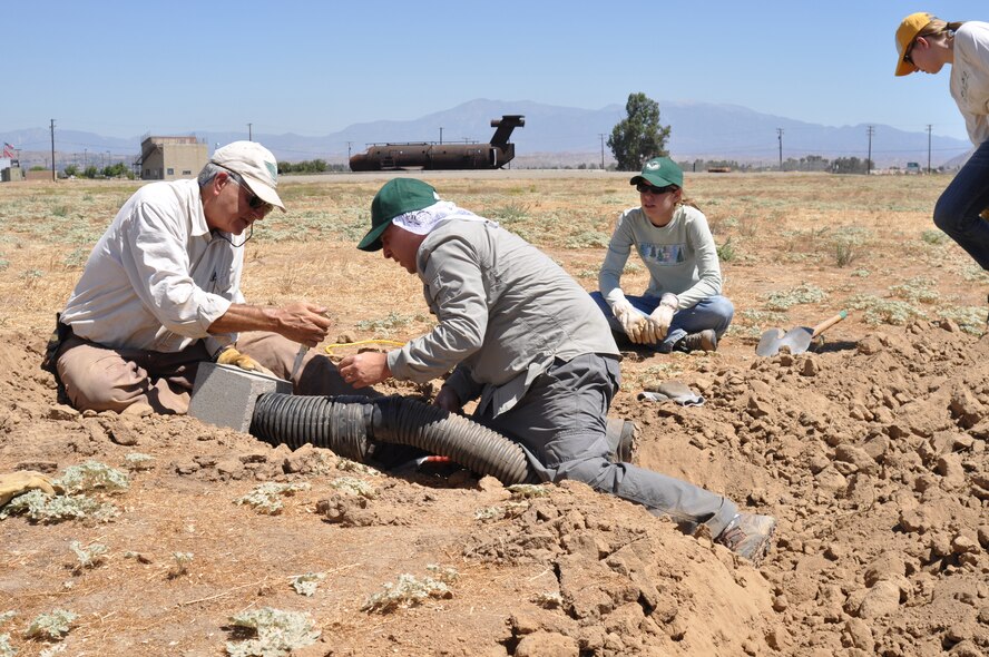 Dr. Jeffrey Lincer and Daniel Palmer, Wildlife Research Institute, fit the end of a piece of irrigation piping into a cinderblock at March Air Reserve Base, Calif., Sept. 1, 2010.  The new burrows are located in a remote section of the base and will serve as habitat for a pair of owls being displaced by the construction of an indoor firing range. Burrowing owls are a Species of Critical Concern in California.  (U.S. Air Force photo/Megan Just)