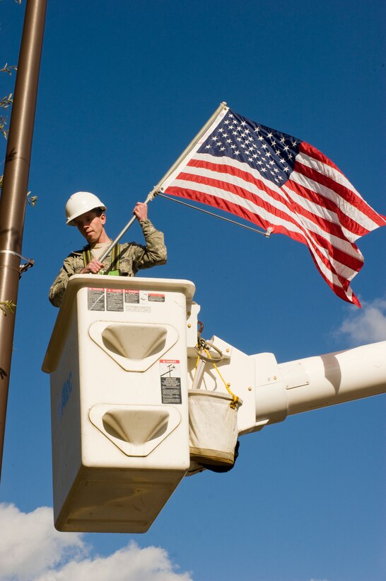 Senior Airman Justin Betterton, 11th Civil Engineer Squadron electrical journeyman, replaces a row of U.S. flags from a bucket truck on Arnold Avenue. Nov. 10. (U.S. Air Force photo/Bobby Jones) 