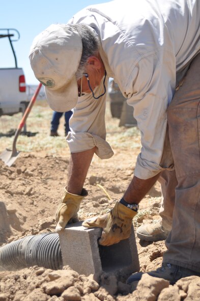 Dr. Jeffrey Lincer, Wildlife Research Institute, fits the end of a piece of irrigation piping into a cinderblock at March Air Reserve Base, Calif., Sept. 1, 2010.  The new burrows are located in a remote section of the base and will serve as habitat for a pair of owls being displaced by the construction of an indoor firing range. Burrowing owls are a Species of Critical Concern in California.  (U.S. Air Force photo/Megan Just)
