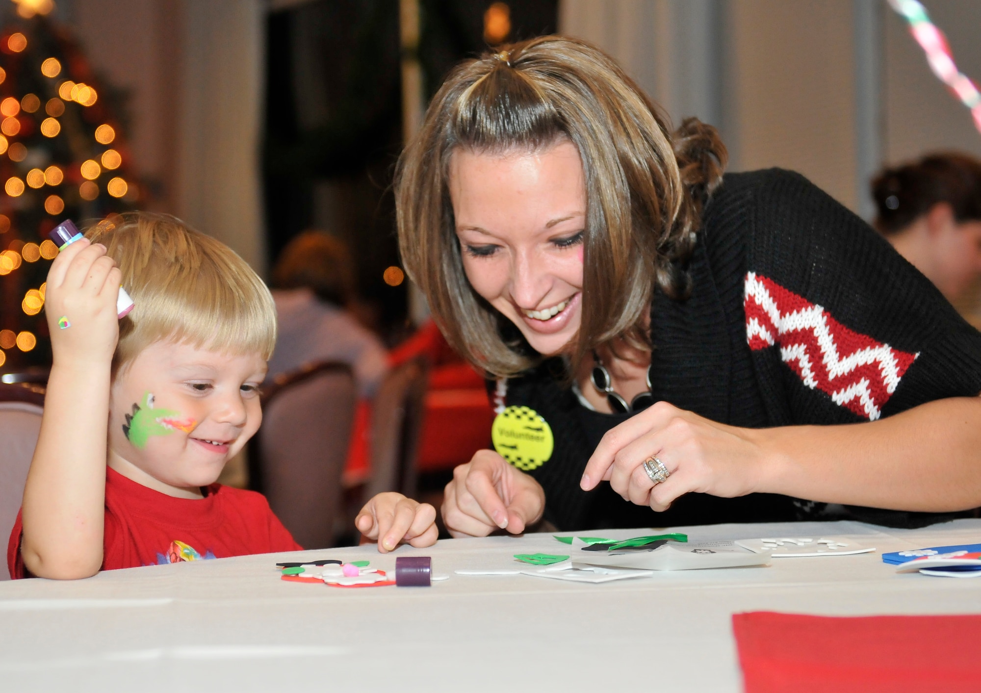 Senior Airman Christen Abner, 325th Comptroller Squadron finance customer service technician, does arts and crafts with a military dependent Nov. 30 during the Hearts Apart Holiday Party at the Heritage Club. (U.S. Air Force photo by Lisa Norman)