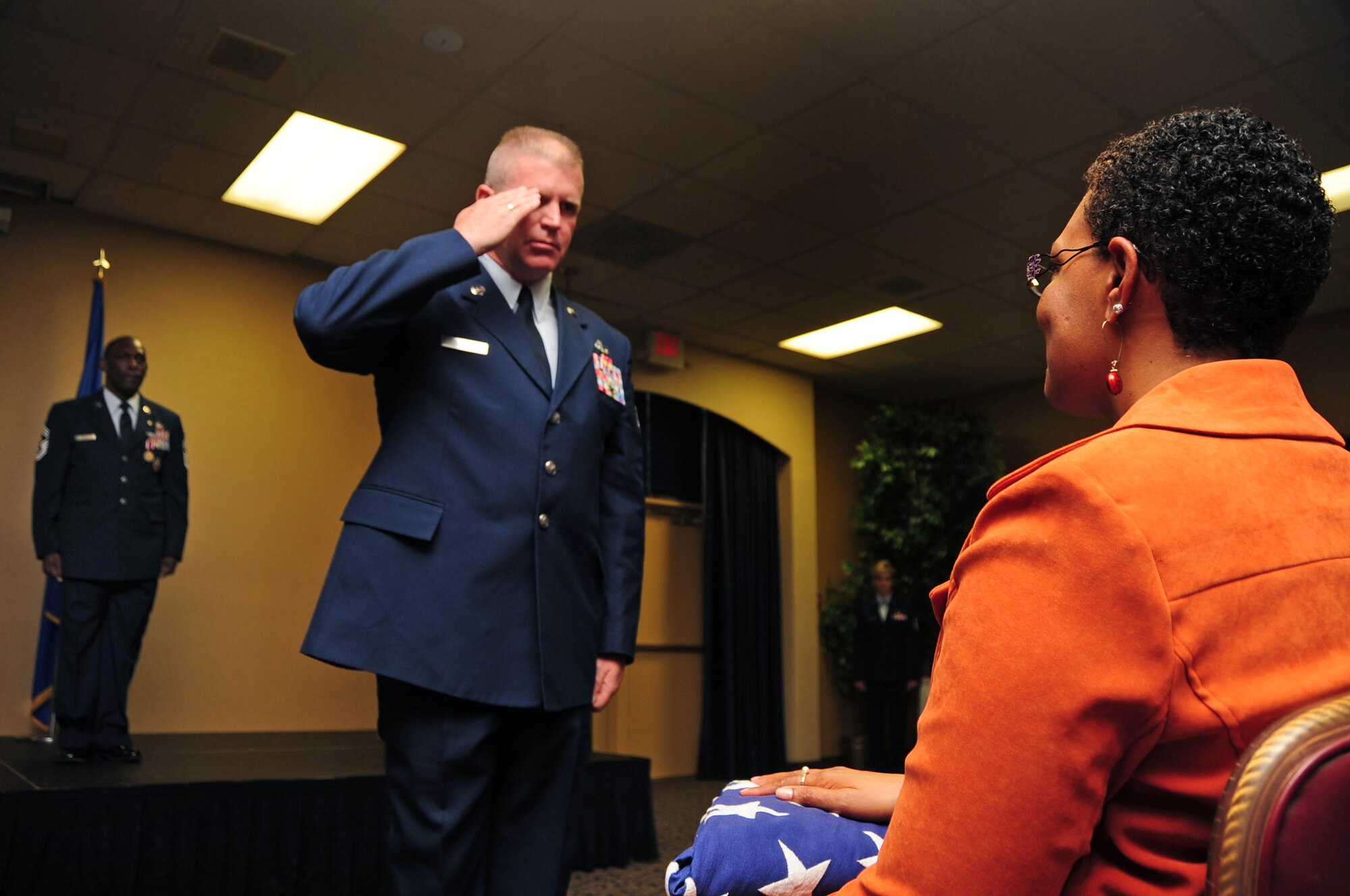 ELLSWORTH AIR FORCE BASE, S.D. -- Chief Master Sgt. Clifton Cole, 28th Bomb Wing command chief, stands on stage as Chief Master Sgt. Harold Clark, 12th Air Force command chief, salutes the retirement flag given to Chief Cole's wife Paula, Dec. 3.  Airmen, coworkers, family and friends of Chief Cole gathered at the Dakota’s Club to pay tribute and recognize him for his 30 years of distinguished service. (U.S. Air Force photo/Senior Airman Anthony Sanchelli)
