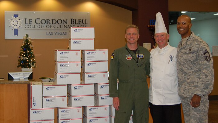 LAS VEGAS-- Honorary 98th Operations Support Squadron Commander, Heinz Lauer, executive chef and culinary department chair of Le Cordon Bleu College of Culinary Arts in Las Vegas; Lt. Col. Donald Borchelt, 98 OSS commander and Chief Master Sgt. Mark Darden, 98th Range Wing superintendent, pose with packaged boxes of holiday cookies at the college Dec. 2. More than 25 students and their instructors spent more than 50 hours baking, decorating and packaging more than 5,500 cookies, which were shipped to Nellis and Creech Airmen currently deployed to Iraq, Afghanistan and Africa.  This is the fifth year Le Cordon Bleu has sent cookies to deployed servicemembers and the school has provided more than 40,000 cookies since starting the program. "We feel good about this program and it's the least we can do to say thank you and support the troops who are keeping us safe and free," Mr. Lauer said. (Courtesy photo)