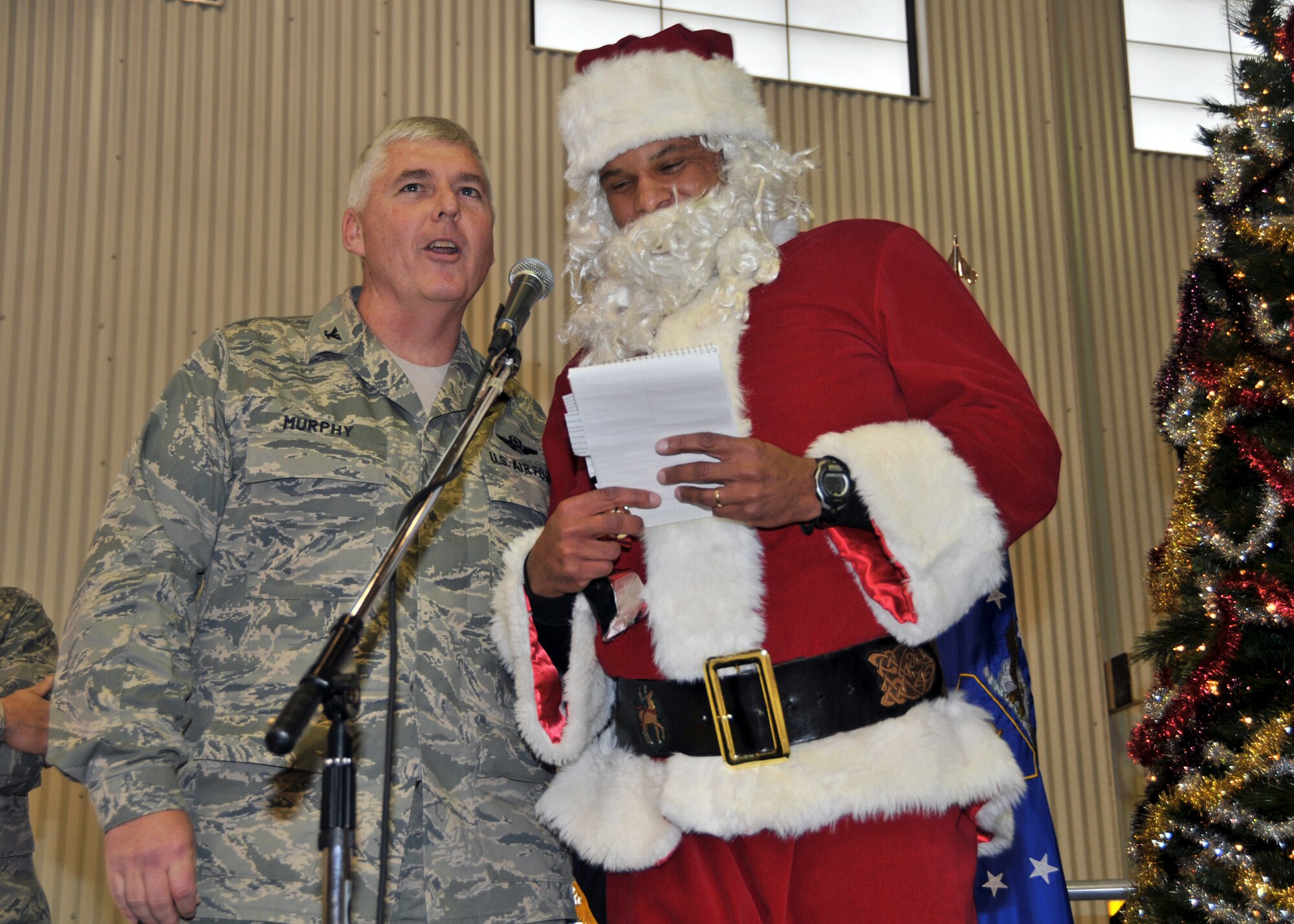 Santa Claus shares the stage with Col. Mark Murphy, acting 914th Airlift Wing commander during a visit to the Niagara Falls Air Reserve Station December 4, 2010 Niagara Falls NY. Mr. Claus read aloud from his naughty or nice list to members of the 914th Airlift Wing during their Holiday part. (U.S. Air Force photo by Staff Sgt. Joseph McKee)