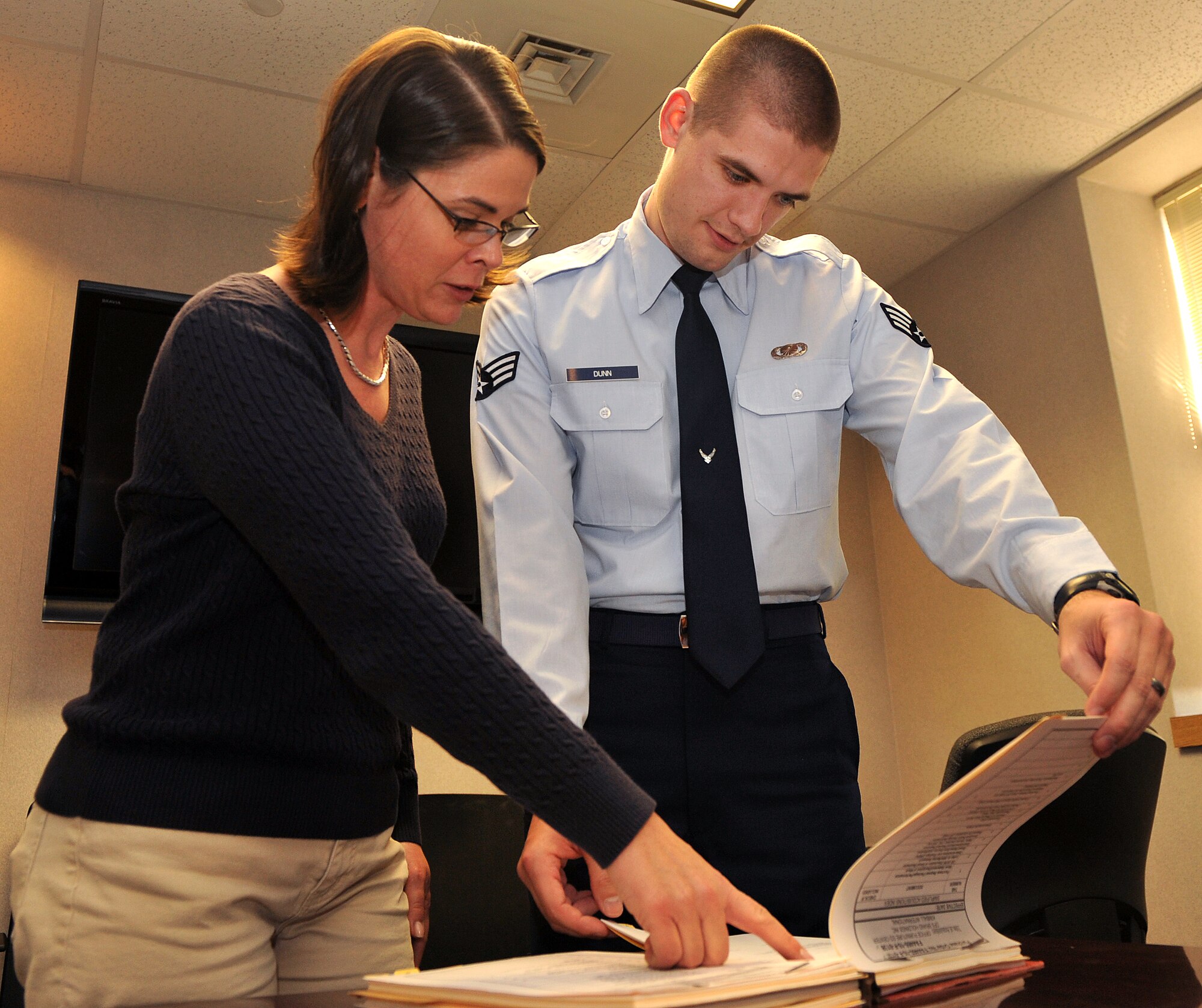 Senior Airman Francis “Elwyn” Dunn, a 19th Contracting Squadron contract specialist, reviews contracts with Valerie Kramer, a 19th CS contracting specialist Dec. 7, 2010, at Little Rock Air Force Base, Ark.  The Airman, a Columbia, S.C., native, earned a bachelor’s degree from the University of South Carolina, an associate’s degree from the  Community College of the Air Force in contracts management and is working toward a master's degree in business operations from the University of Arkansas. (U.S. Air Force photo by Senior Airman Gul Crockett)