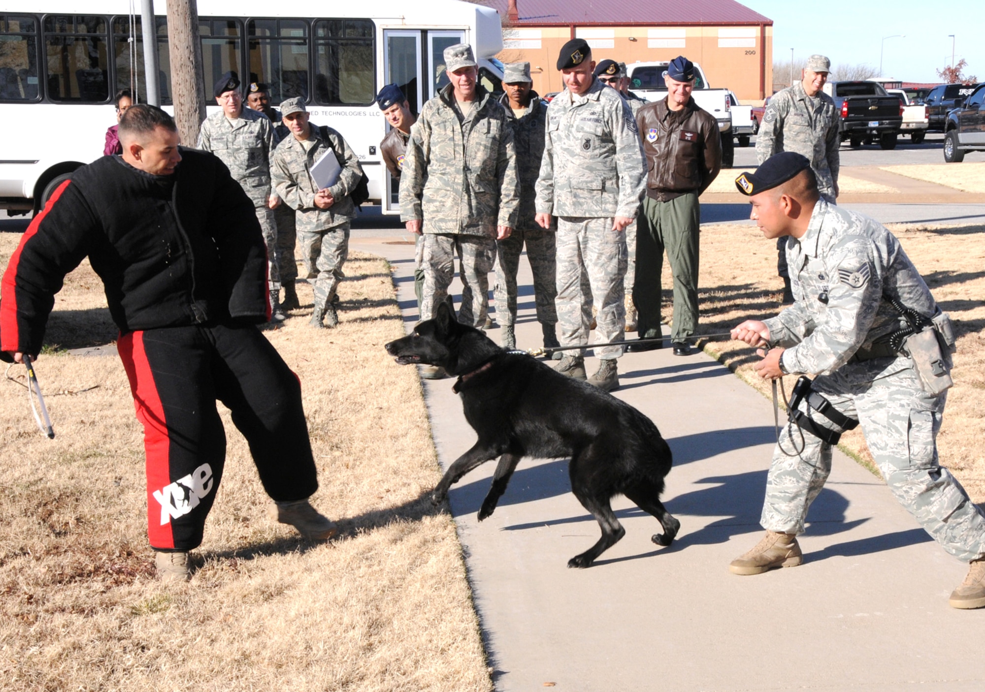 With Maj. Gen. Mark Solo, 19th Air Force commander, and 71st Flying Training Wing senior leadership looking on, Staff Sgt. Juventino Salazar, front right, a military working dog handler with the 71st Security Forces Squadron, and his dog, Cini, prepare to demonstrate aggression training with the help of Staff Sgt. Gary Eyster, right, a dog trainer with the 71st SFS. The demonstration was part of General Solo’s tour of Vance AFB Nov. 30 and Dec. 1, his first since taking command of 19th Air Force in July. (U.S. Air Force photo/ Terry Wasson)