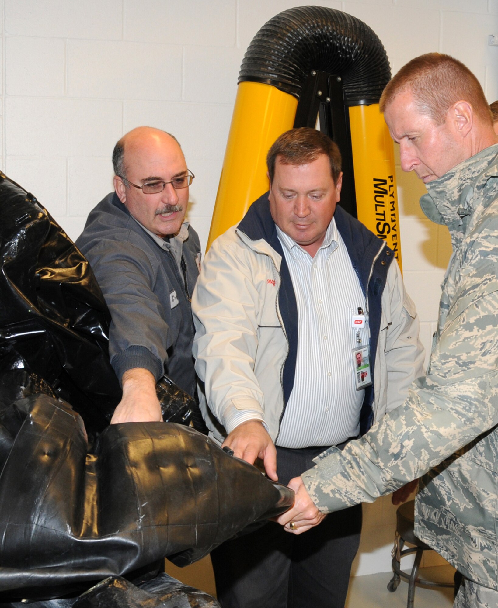 Maj. Gen. Mark Solo, 19th Air Force commander, right, is shown both a new and old fuel bladder from a T-38 Talon jet trainer at the Vance AFB Fuel System Maintenance facility during his first visit to the base since taking command of 19th AF. Doug Cole, center, director of aircraft maintenance and Greg Cohlmia, left, Fuels leadman, both with CSC Applied Technologies, gave the general a tour of the new fuel cell test facility. (U.S. Air Force photo/ Terry Wasson)