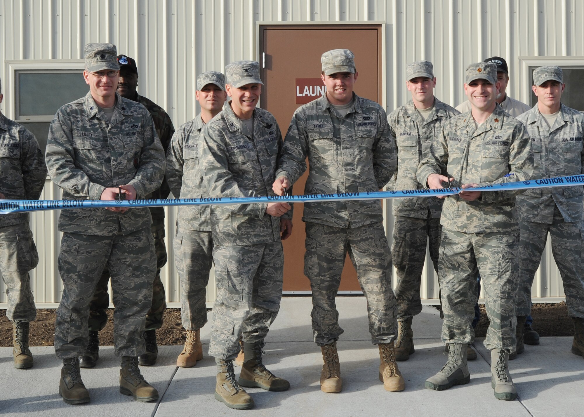 Lt. Col. Louis Lilley, 22nd Civil Engineer Squadron commander, Col. Jamie Crowhurst, 22nd Air Refueling Wing commander, Senior Airman Dakota Tyree, 22nd Civil Engineer Squadron electrical systems journeyman, and Maj. Colin Huckins, 22nd Force Support Squadron commander, cut a caution tape to mark the opening of the communal showers and laundry facilities located by the Krueger Recreational Area ponds Dec. 3, 2010, McConnell Air Force Base, Kan. The construction, which lasted approximately five months, was designed to train Airmen about similar structures that they will build in a deployed environment. The project was built from the bare foundation to the roof, to include the concrete pad, electrical, plumbing and heating and ventilation. (U.S. Air Force photo/Airman 1st Class Katrina M. Brisbin)