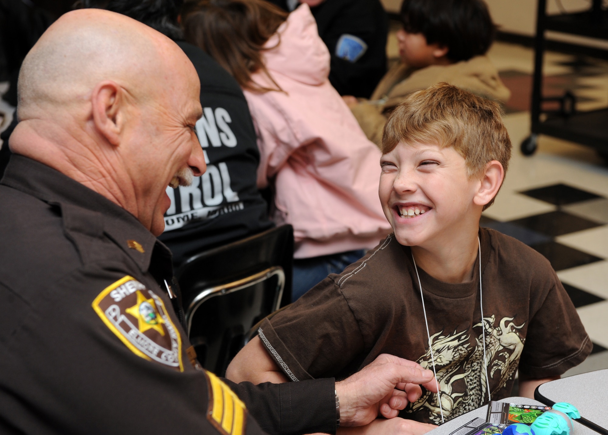 MOUNTAIN HOME, Idaho – Sergeant Rudy Foote, Elmore County Police Department officer, laughs with Fredrick, 9, before going shopping during the shop with a cop event held in Mountain Home, Dec. 4. Children in the shop with a cop program are referred by local agencies and school programs. This year more than 100 children were provided with the chance to make this Christmas one to remember. (U.S. Air Force photo by Senior Airman Debbie Lockhart)