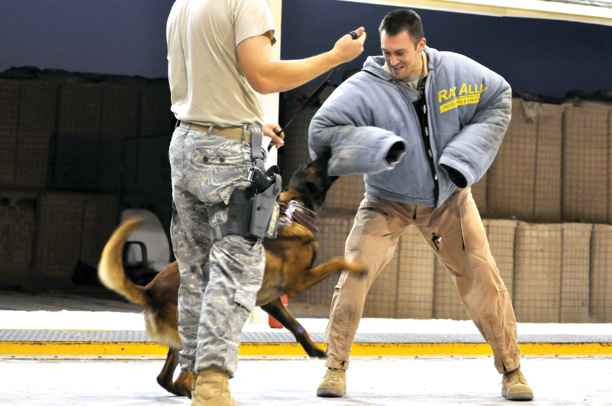 Capt. Brian McReynolds, 746th Expeditionary Airlift Squadron,  gets the opportunity to experience what it’s like to be a military working dog handler during a demonstration here Nov. 12. Vvadar the working dog attacks on command as Captain Reynolds pretends to be a perpetrator. The dogs are not only  taught to detect explosives, they are taught to protect their handlers in dangerous and life -threatening situations. U.S. Air Force photo/Staff Sgt. Nika Glover  