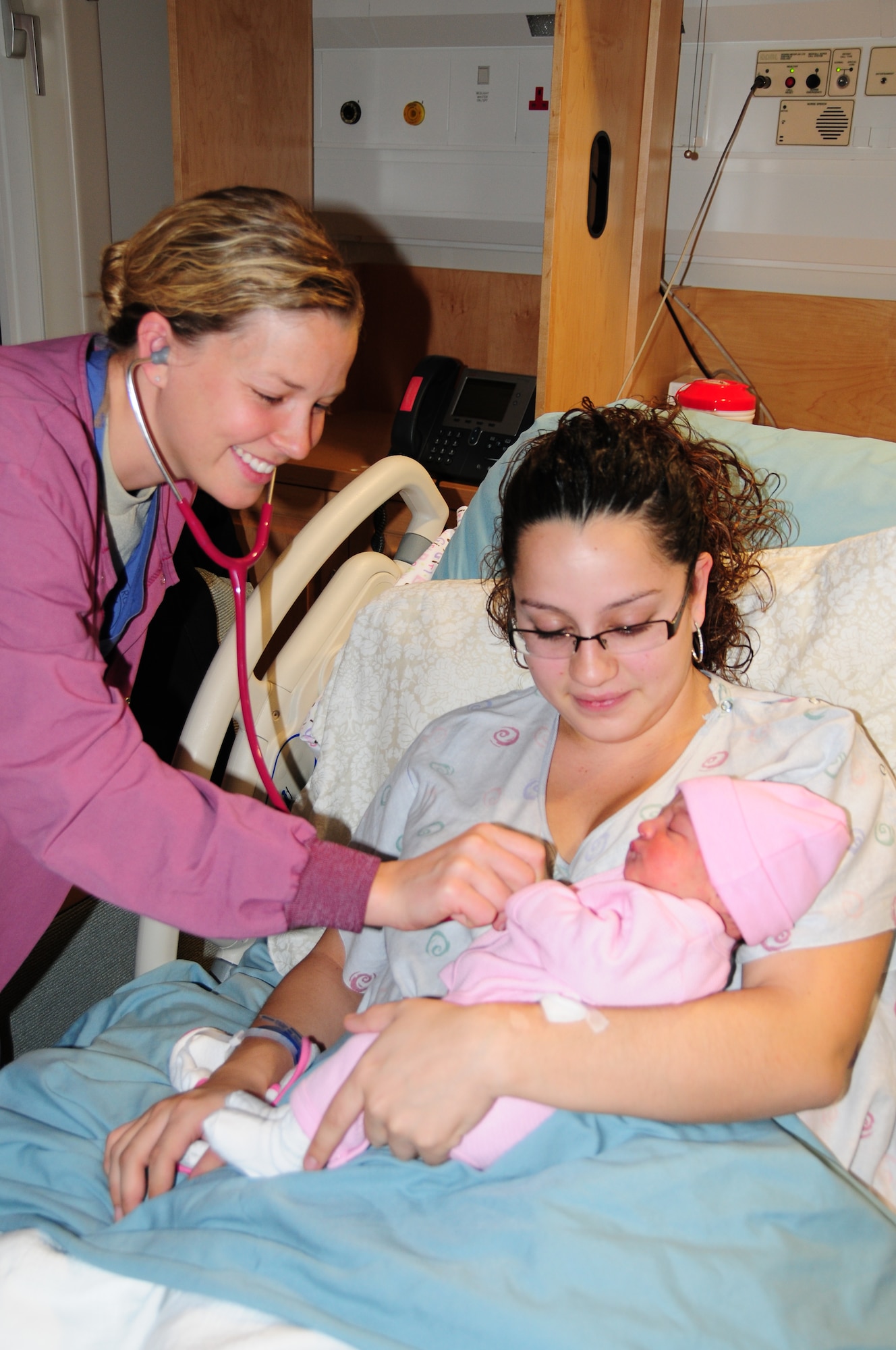 ROYAL AIR FORCE LAKENHEATH, England – Capt. Jessica Wyche, 48th Inpatient Squadron clinical nurse, examines newborn Isabella Garcia as her mother Juliana watches Dec. 3. The 48th Inpatient Squadron Maternal Child Unit supports 40 to 50 births each month. (U.S. Air Force photo/Senior Airman David Dobrydney)