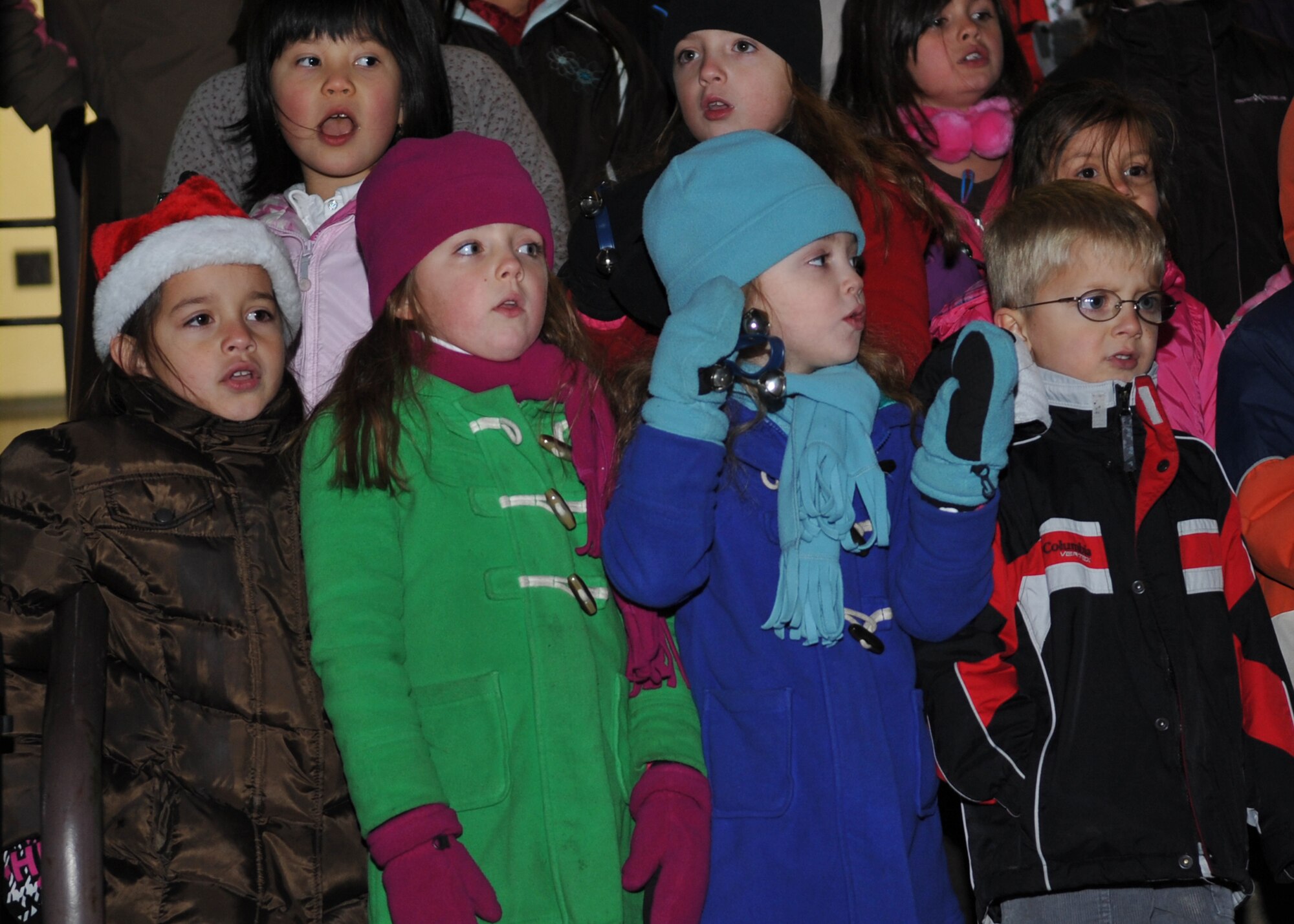 Children from Osan American Elementary School sing during the base holiday tree lighting ceremony Dec. 6.  The tree lighting ceremony took place in front of the base theater.  The event included a tree lighting cowntdown, music performances by Osan American Elementary School, Santa's arrival, and free hot chocolate. (U.S. Air Force Photo/ Senior Airman Evelyn Chavez)