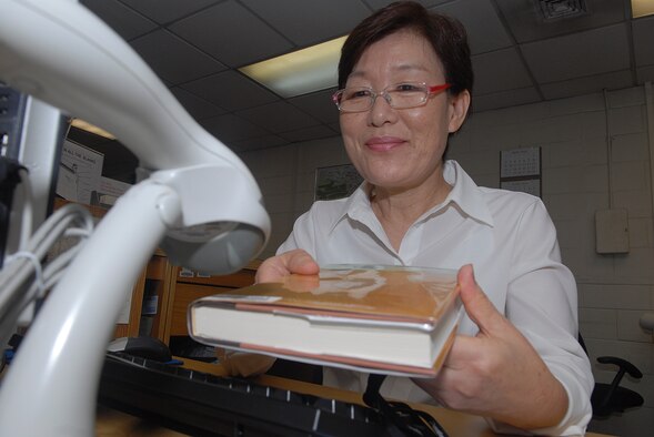 KUNSAN AIR BASE -- Ms. Yi, Sung A., 8th Force Support Squadron base library clerk checks a book out for a customer. Ms. Yi has worked at the library since 1987, cataloging books and other library materials as well as working at the front desk to provide customer service. Civilian employees provides continuity  of support, which is vital to the success of 8th FSS mission to the Wolf Pack community. (U.S. Air Force photo)


