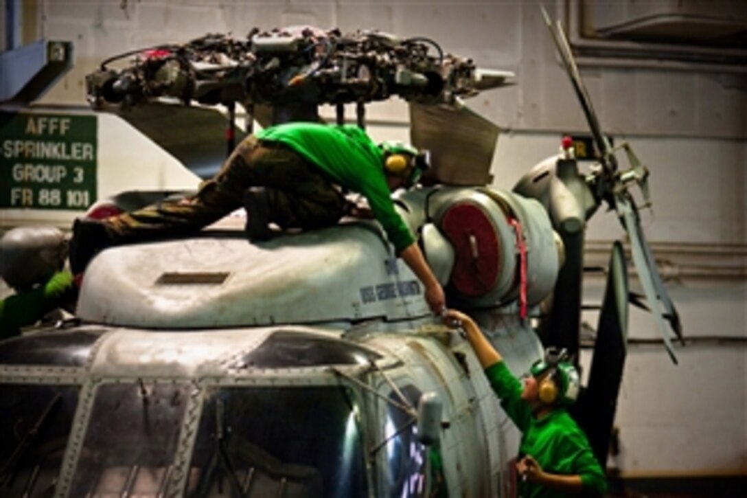 Aviation mechanics assigned to Helicopter Anti-Submarine Squadron 14 perform maintenance on the main rotor of an SH-60 Sea Hawk helicopter aboard the aircraft carrier USS George Washington (CVN 73) underway in the Pacific Ocean on Dec. 5, 2010.  The George Washington is participating in Keen Sword 2011 with the Japan Maritime Self-Defense Force through Dec. 10.  