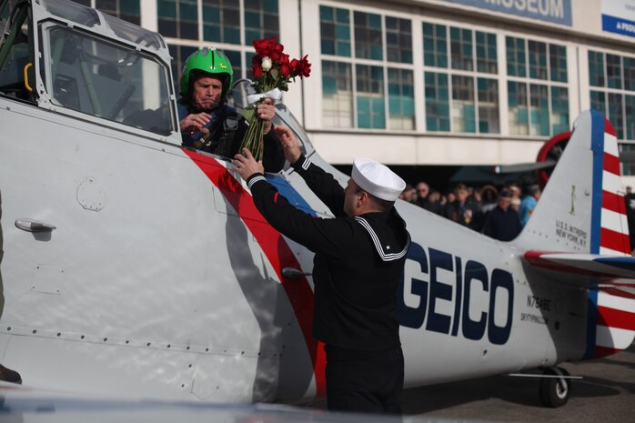 FARMINGDALE, N.Y. -- A sailor hands a set of roses to Joe Daly before departing for the Statue of Liberty at the conclusion of the Dropping of the Roses / Pearl Harbor Memorial Ceremony, here, Dec. 7. This is the 20th year of a tradition started by the late Joseph Stanley Hydrusko to honor those he served with at Pearl Harbor, Hawaii. Each year roses are dropped over the Statue of Liberty marking the time of the attack. In the attack, 21 ships were sunk or damaged, 188 aircraft were destroyed, and 2,335 service members were killed. America answered with an island-hopping campaign culminating with the iconic Marine Corps flag raising on Iwo Jima more than three years later. (Official Marine Corps photo by Sgt. Randall A. Clinton / RELEASED)