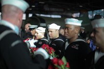 FARMINGDALE, N.Y. -- A detachment of sailors hold 69 American Roses to be blessed and loaded into a WWII-era airplane and eventually dropped over the Statue of Liberty, at 12:55 pm to commemorate the exact time of the attack on Pearl Harbor, Hawaii, here, Dec. 7. This is the 20th year of a tradition started by the late Joseph Stanley Hydrusko to honor those he served with at Pearl Harbor. In the attack, 21 ships were sunk or damaged, 188 aircraft were destroyed, and 2,335 service members were killed. America answered with an island-hopping campaign culminating with the iconic Marine Corps flag raising on Iwo Jima more than three years later. (Official Marine Corps photo by Sgt. Randall A. Clinton / RELEASED)