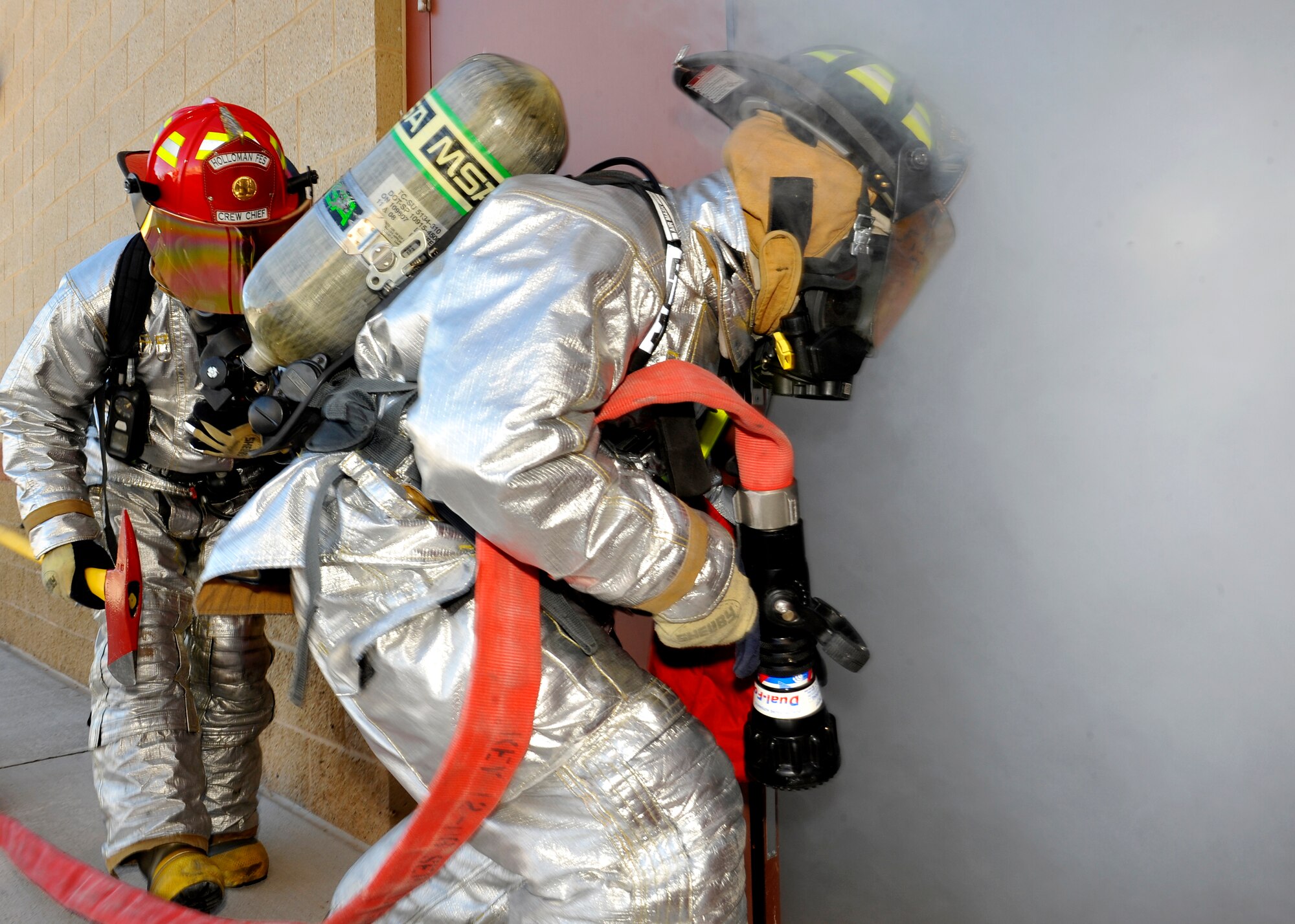 HOLLOMAN AIR FORCE BASE, N.M. -- Staff Sgt. Michael Jones and Airman 1st Class Tristan Cooper, with the 49th Civil Engineer Squadron firefighters, prepare to enter a smoke filled room during a monthly structural fire exercise Dec. 1, 2010. Sergeant Jones and Airman Cooper also conducted a primary search inside the smoke filled room to rescue any occupants and to ensure the fire was out. Throughout the year firefighters are required to perform egress training on the F-22 Raptor, GR1 Tornado and the T-38 aircraft as well. They also train on hazardous materials, confined spaces and special operations to maintain their Defense International Fire Service Accreditation Congress certifications. (U.S. Air Force by Senior Airman Veronica Stamps/Released)