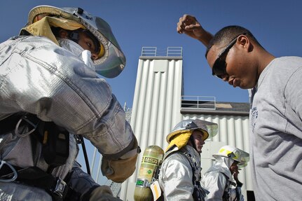 Randolph AFB, TX, 4 December 2010:  
Staff Sgt David Hicks with the 902nd Security Forces Squadron watches as Senior Airman Trevor Alexis, 902nd Civil Engineering Divisions fire department, demonstrates the hand-over-hand method for pulling a hose at the end of a rope to the top of the training tower during the fire relay of the Battle of the Badges where firefighters and security forces experience aspects of each others jobs and build camaraderie. 
(U.S. Air Force photo/Steve Thurow)