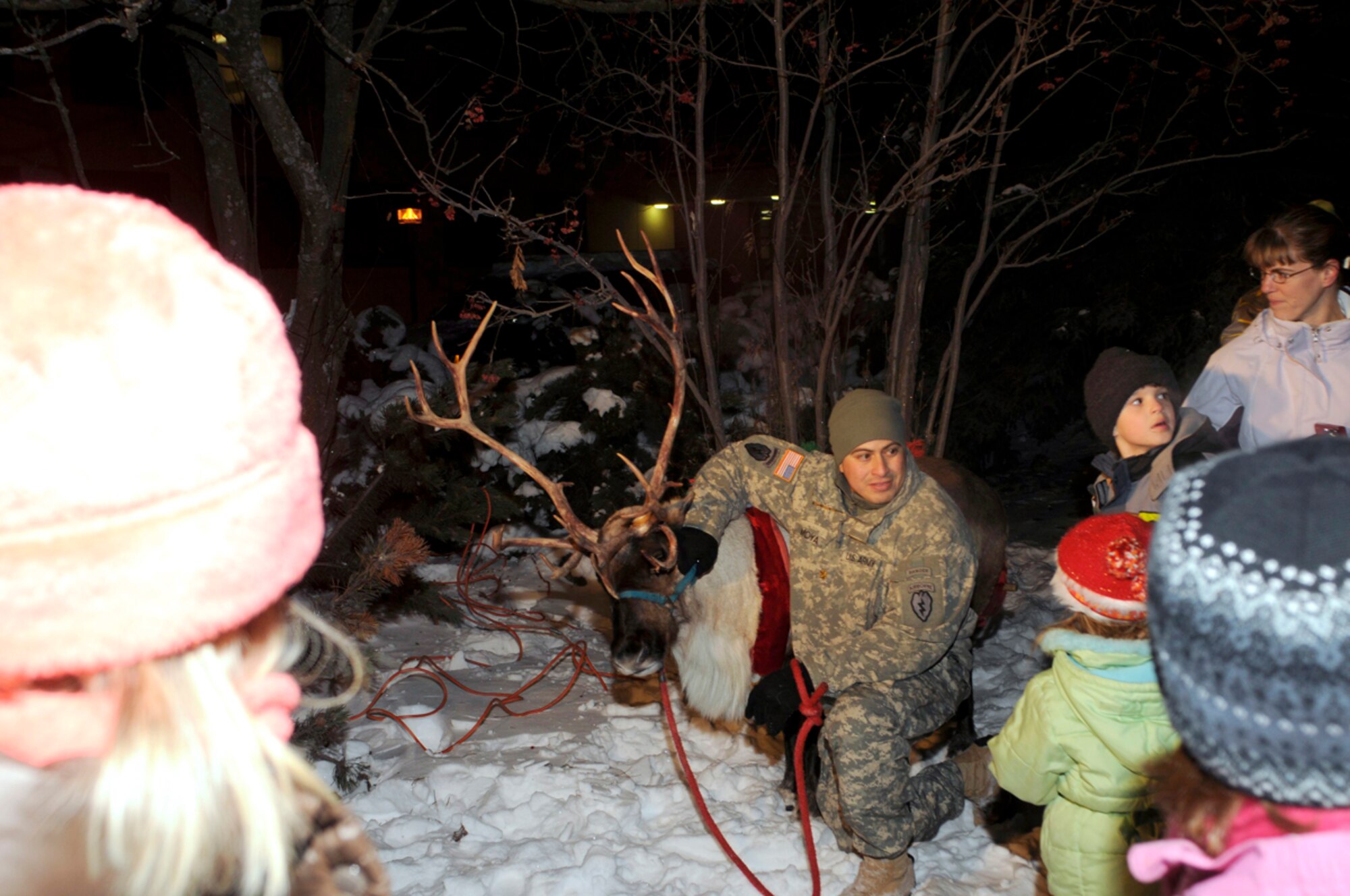 Army Maj. Carlos Moya, HHC, 4th Brigade Combat Team (Airborne), 25th Infantry Division, with Rudolf, answers questions from children at the tree lighting ceremony in front of the headquarters building. (U.S. Air Force photo/Steven White)
